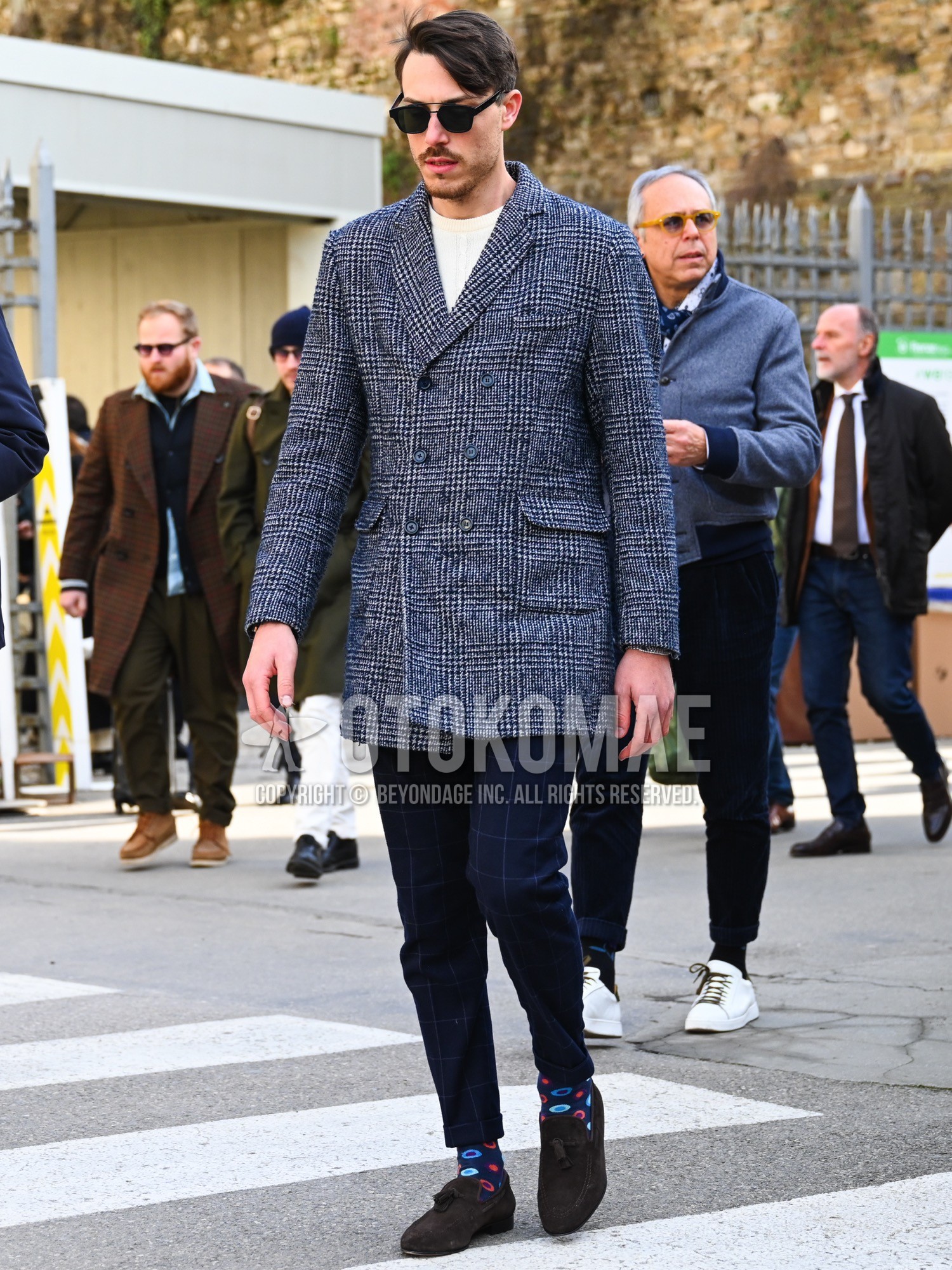 Men's autumn winter outfit with black plain sunglasses, navy check chester coat, white plain sweater, navy check slacks, navy graphic socks, brown tassel loafers leather shoes.
