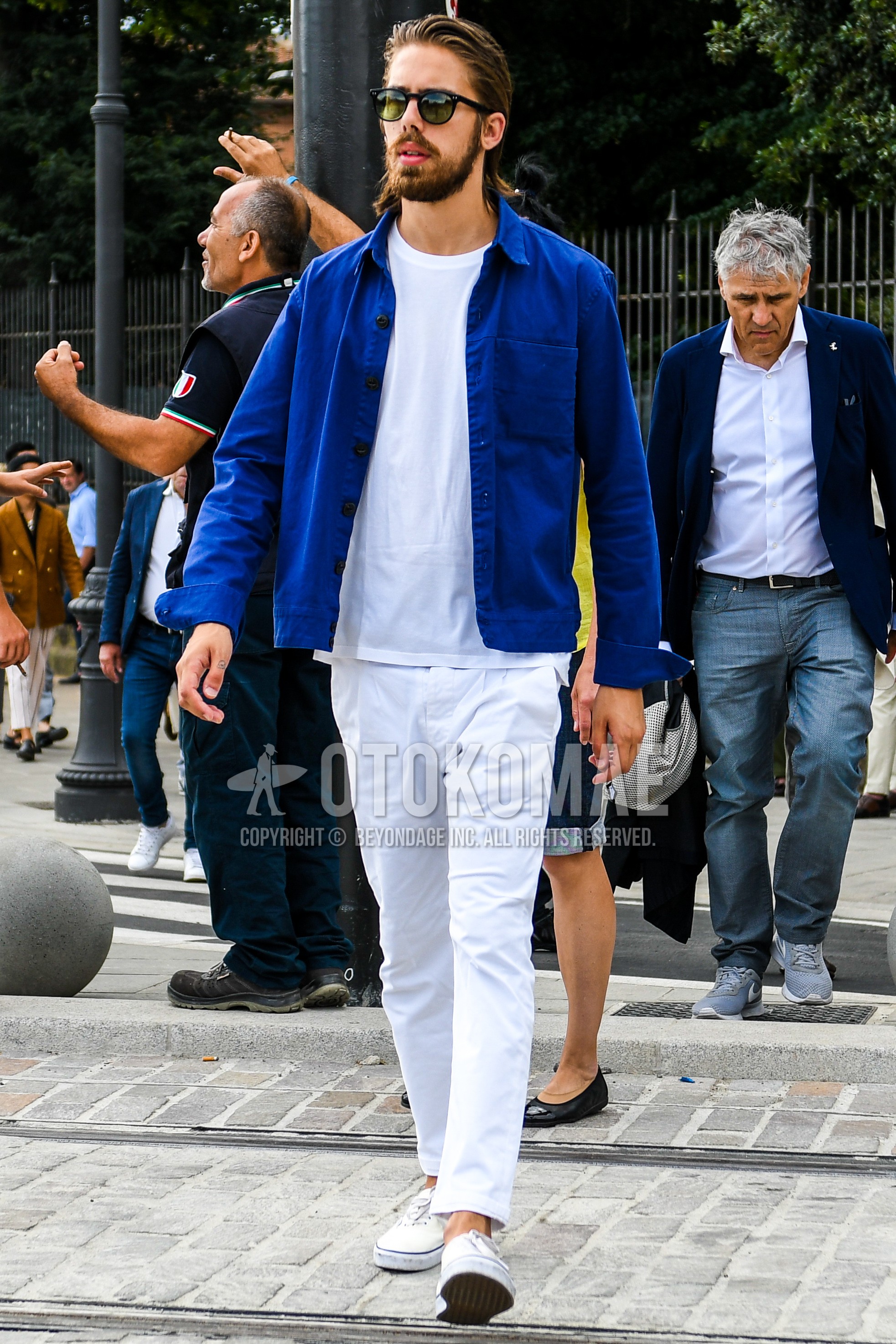 Men's spring summer autumn outfit with plain sunglasses, blue plain shirt jacket, white plain t-shirt, white plain ankle pants, white low-cut sneakers.