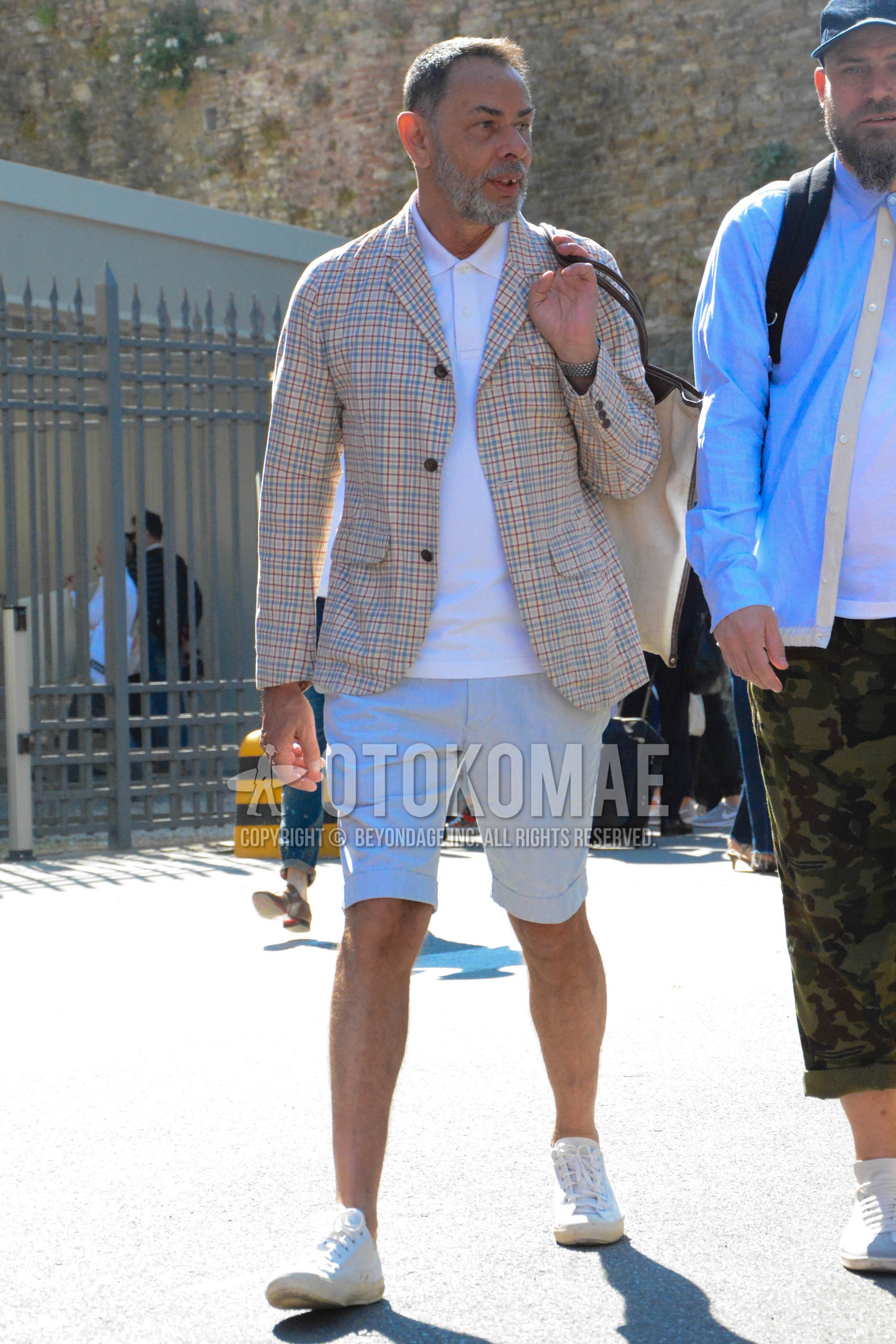 Men's summer outfit with beige check tailored jacket, white plain polo shirt, gray plain short pants, white low-cut sneakers.