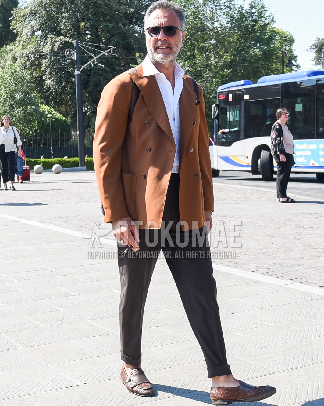 Men's spring summer autumn outfit with black plain sunglasses, brown plain tailored jacket, white plain shirt, brown plain slacks, brown  loafers leather shoes, brown plain backpack.