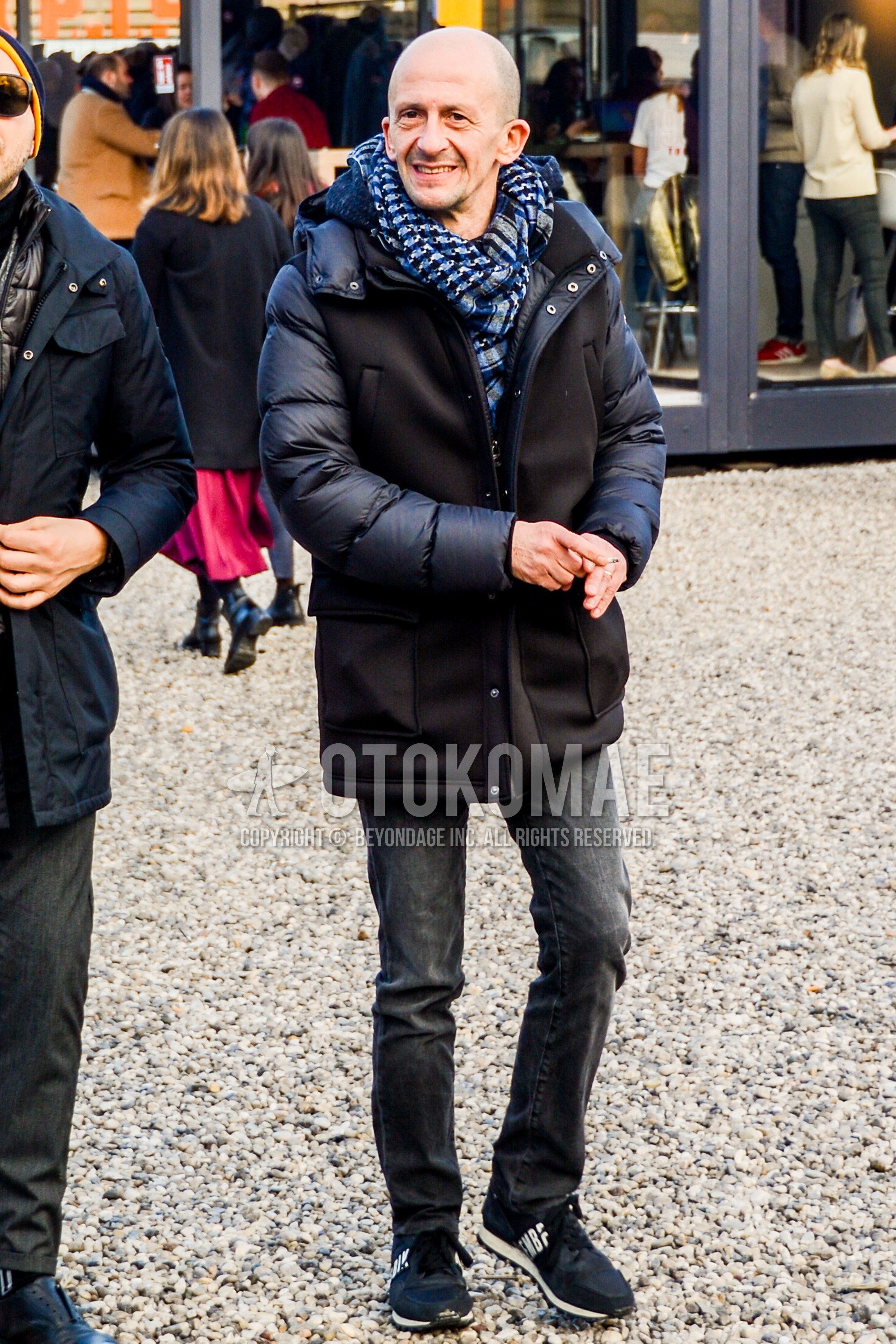 Men's winter outfit with navy scarf scarf, black plain down jacket, dark gray plain denim/jeans, black low-cut sneakers.