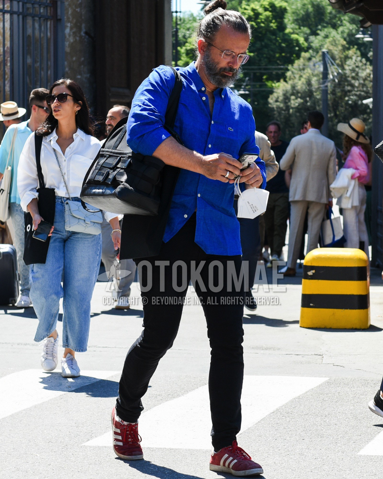 Men's spring summer outfit with black plain glasses, blue plain shirt, black plain chinos, red low-cut sneakers, black plain tote bag, black plain backpack.