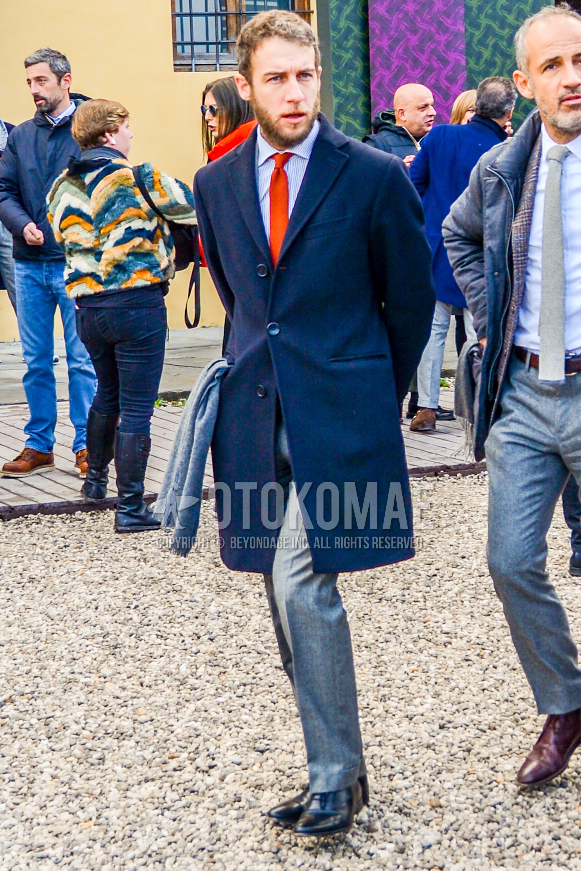 Men's autumn winter outfit with gray plain chester coat, white light blue stripes shirt, gray plain slacks, black straight-tip shoes leather shoes, orange plain necktie.