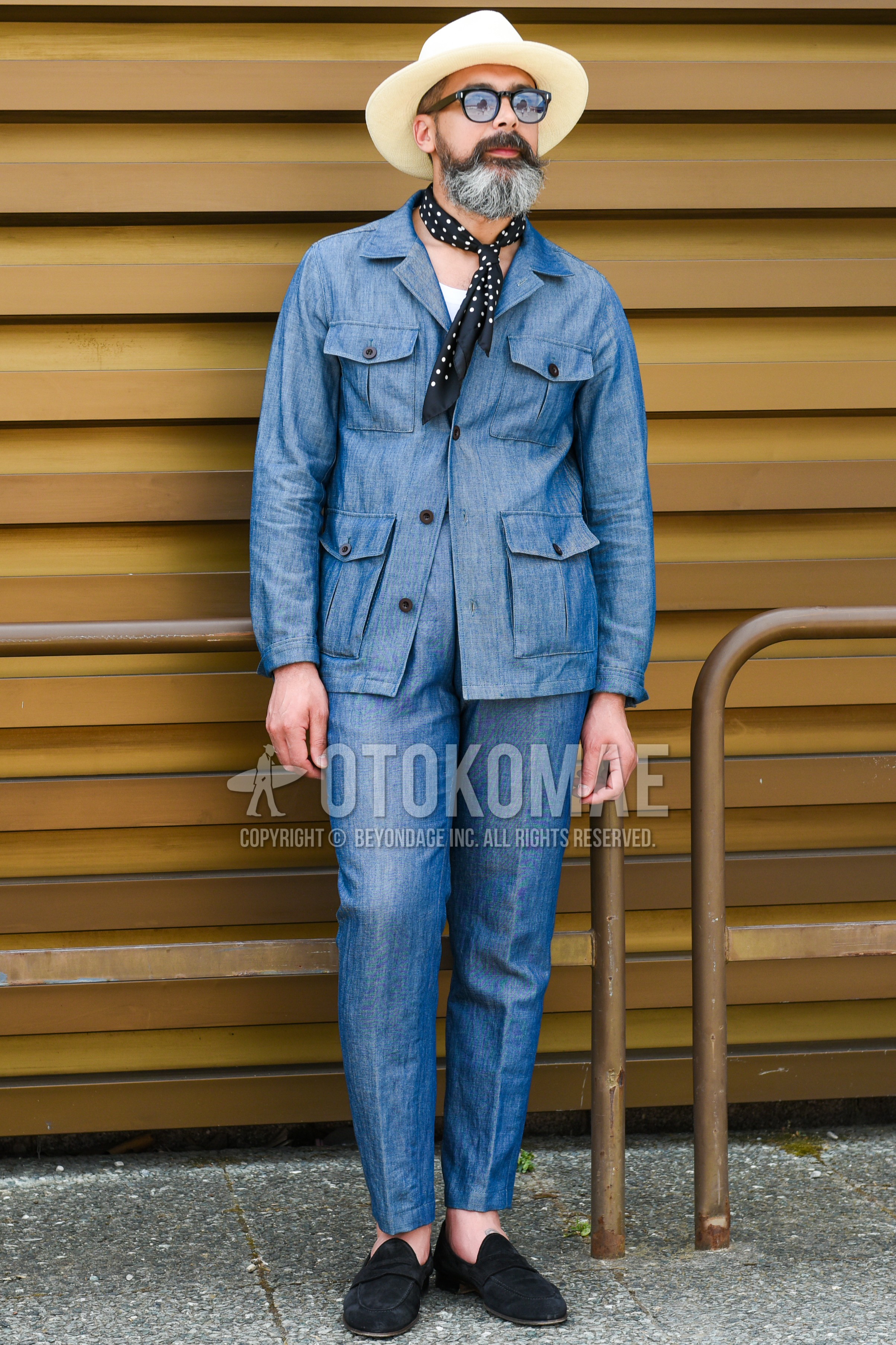 Men's spring summer autumn outfit with beige plain hat, clear plain sunglasses, black dots bandana/neckerchief, blue plain field jacket/hunting jacket, white plain t-shirt, blue plain slacks, black coin loafers leather shoes.