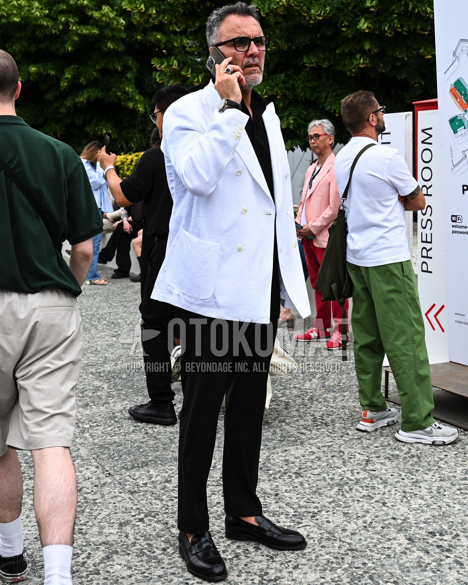 Men's spring summer autumn outfit with black plain sunglasses, white plain tailored jacket, black plain shirt, black plain chinos, black coin loafers leather shoes.