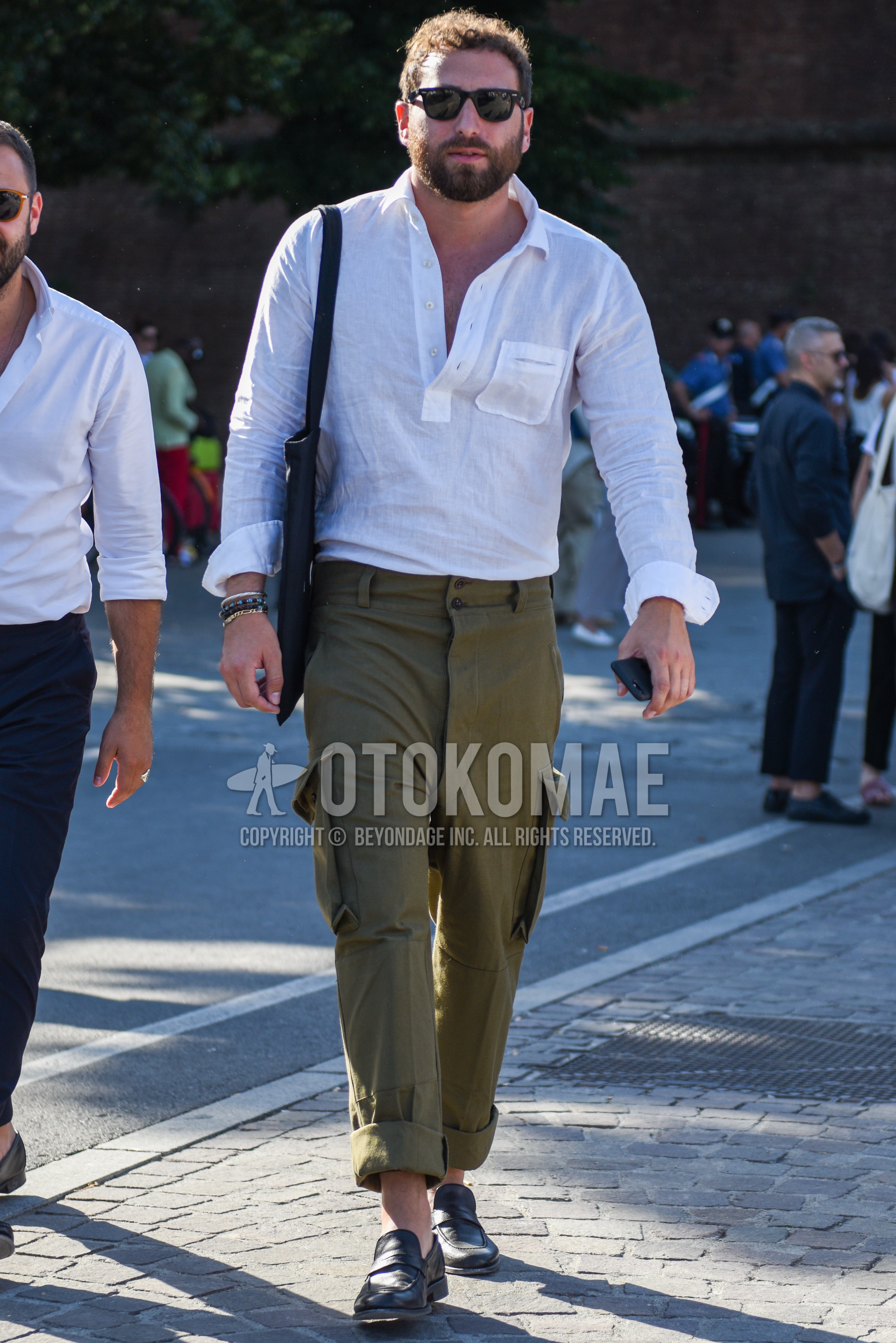 Men's spring summer autumn outfit with black plain sunglasses, white plain shirt, olive green plain cargo pants, black coin loafers leather shoes.