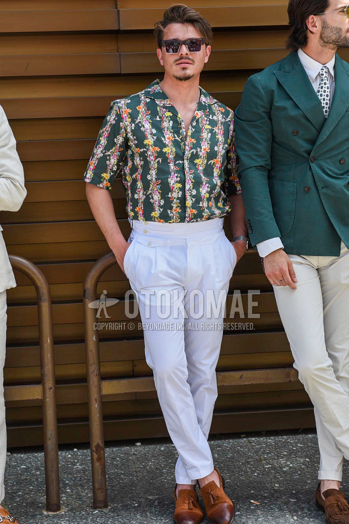 Men's summer outfit with black plain sunglasses, green botanical shirt, white plain beltless pants, brown tassel loafers leather shoes.