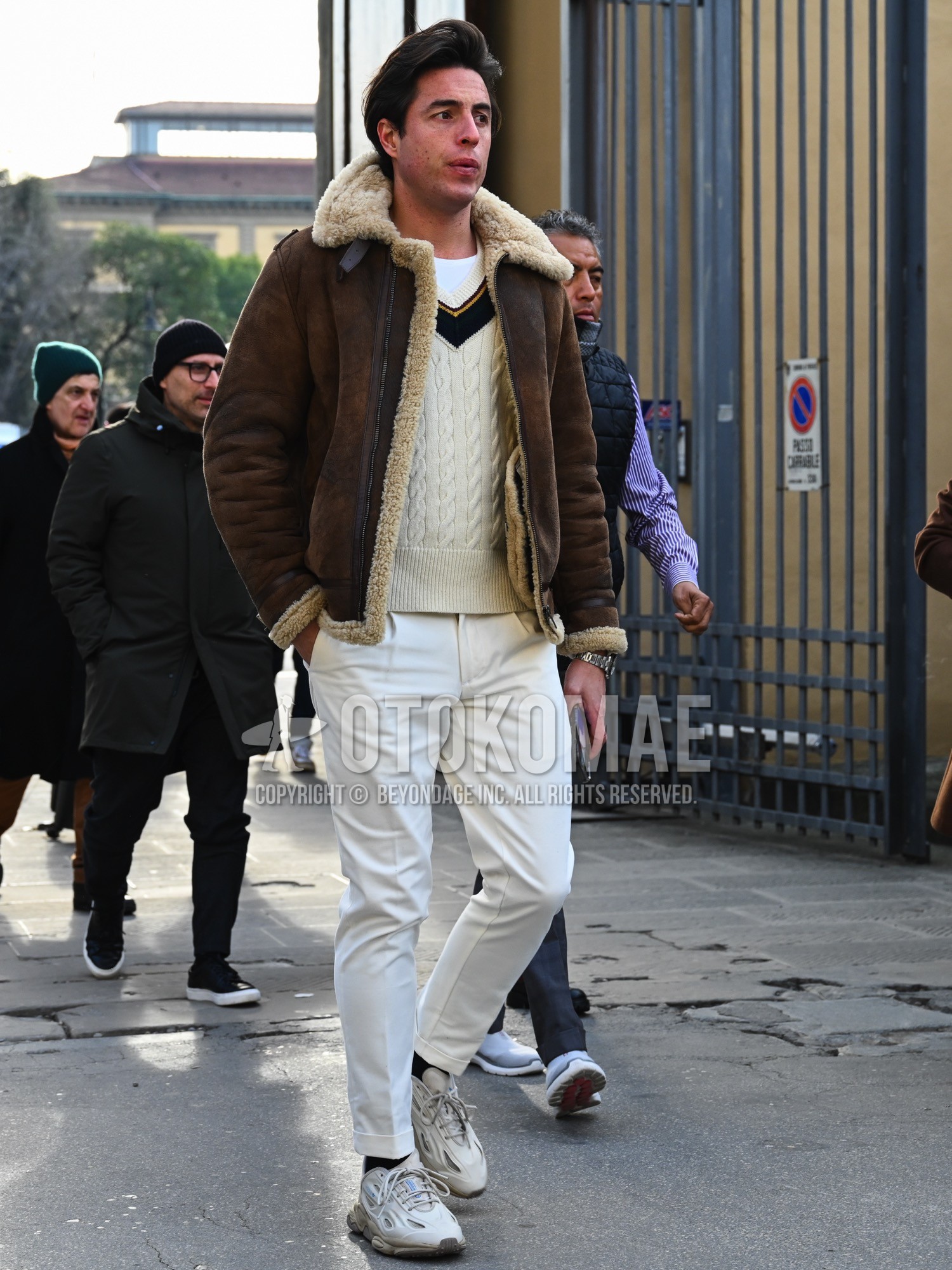 Men's autumn winter outfit with brown plain leather jacket, white plain sweater, white plain t-shirt, white plain slacks, black plain socks, white low-cut sneakers.