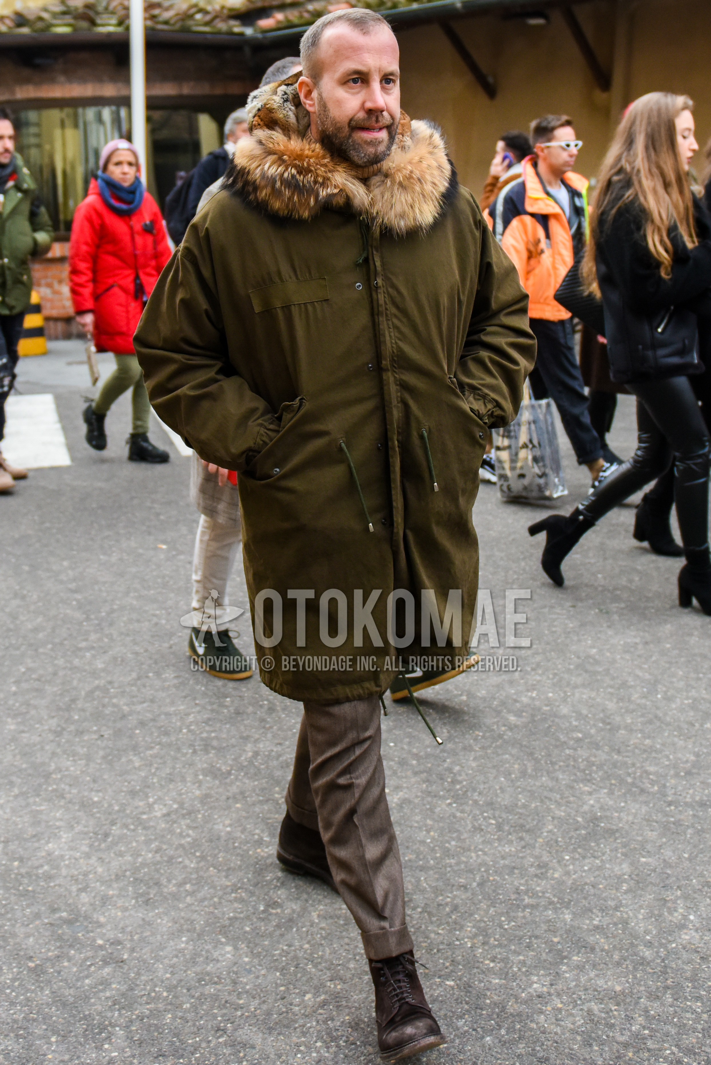 Men's winter outfit with olive green plain mod coat, brown plain slacks, brown  boots.