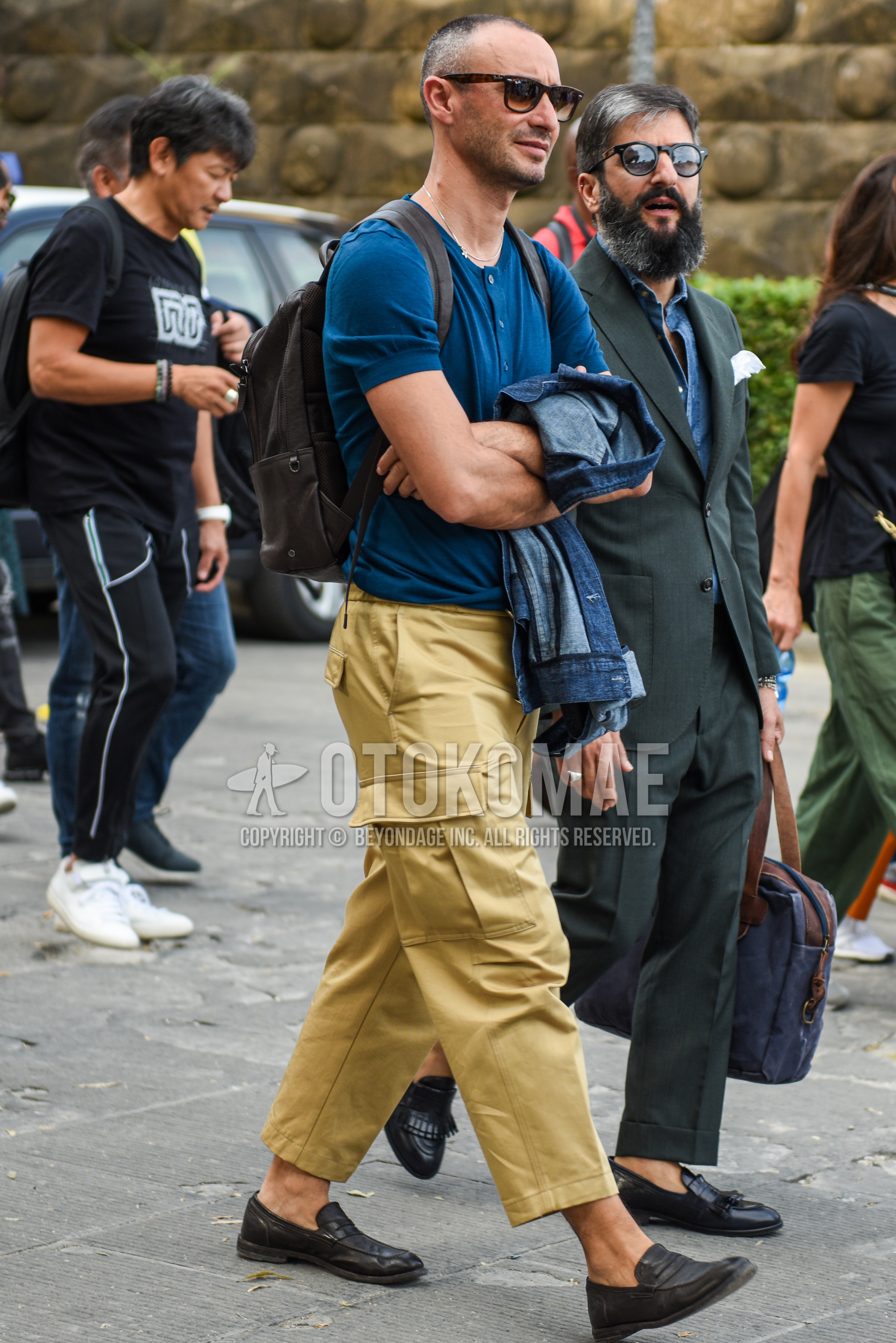 Men's summer outfit with brown tortoiseshell sunglasses, blue plain t-shirt, beige plain damaged jeans, plain cropped pants, plain cargo pants, black coin loafers leather shoes, brown plain backpack.