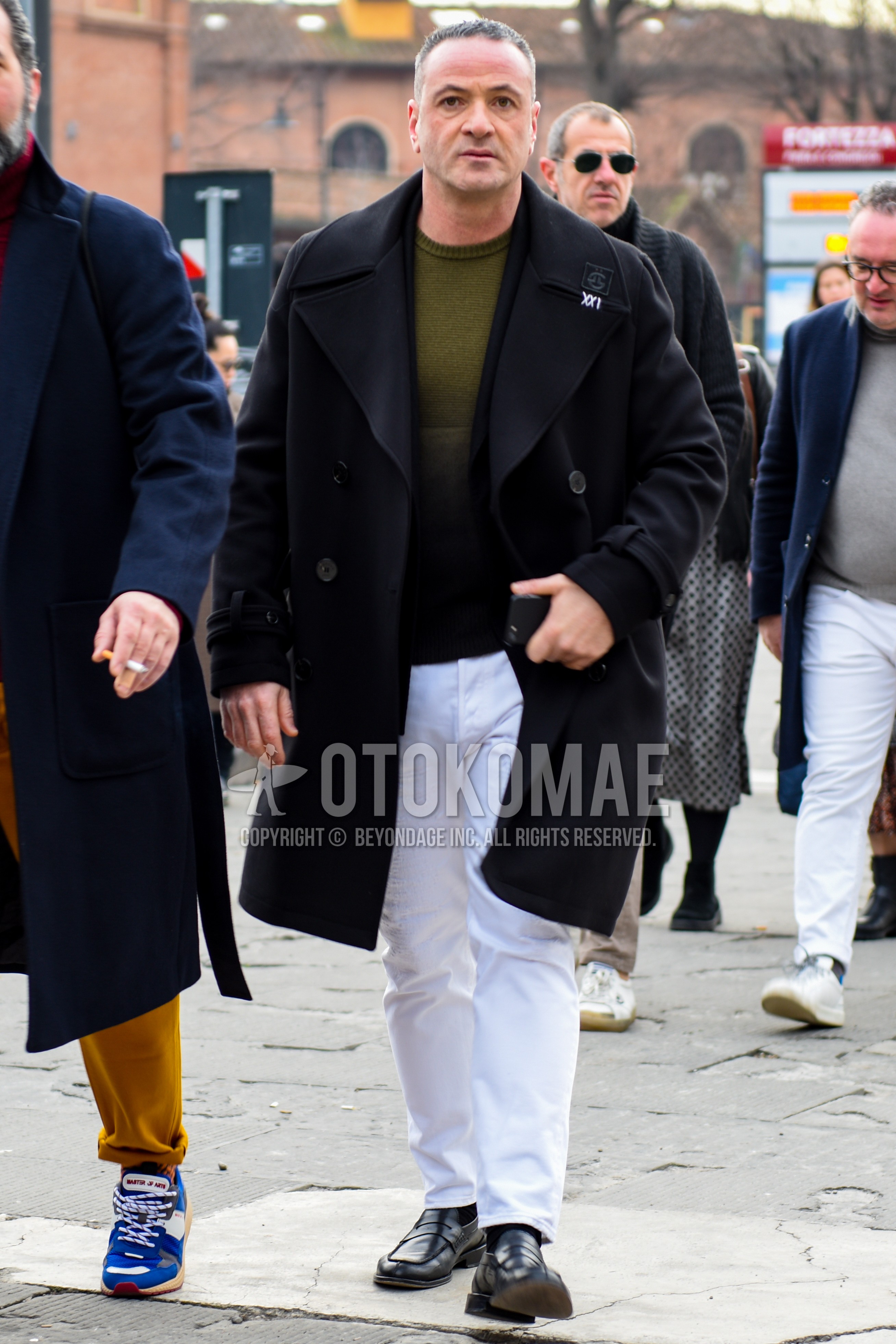 Men's autumn winter outfit with black one point ulster coat, olive green plain sweater, white plain cotton pants, white plain socks, black coin loafers leather shoes.