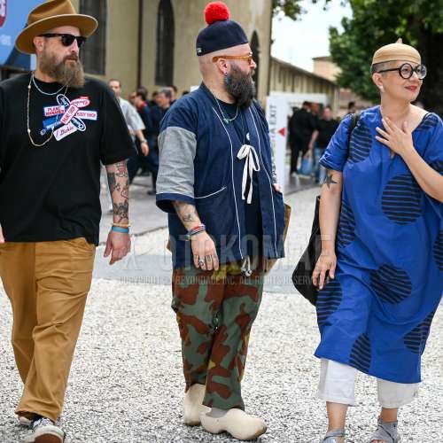 レッド・黒キャップのニットキャップ、オレンジべっ甲のメガネ、ブルー無地のデニムジャケット、ネイビー無地のTシャツ、マルチカラー迷彩のイージーパンツ、白無地のソックス、白サンダルを合わせた夏春のメンズコーデ・着こなし。