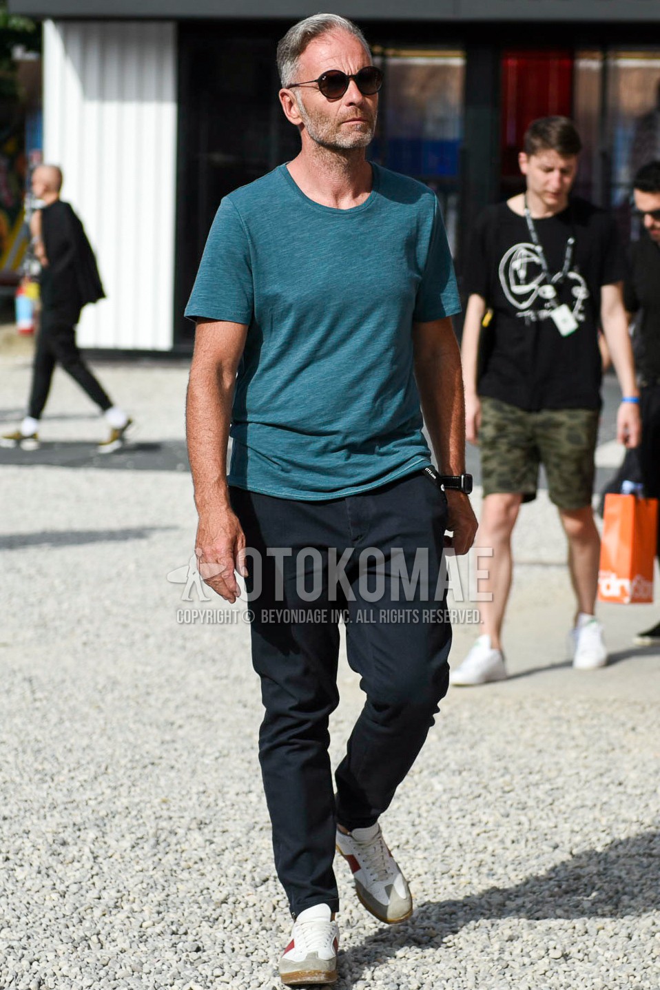 Men's summer outfit with plain sunglasses, blue plain t-shirt, black plain chinos, white low-cut sneakers.