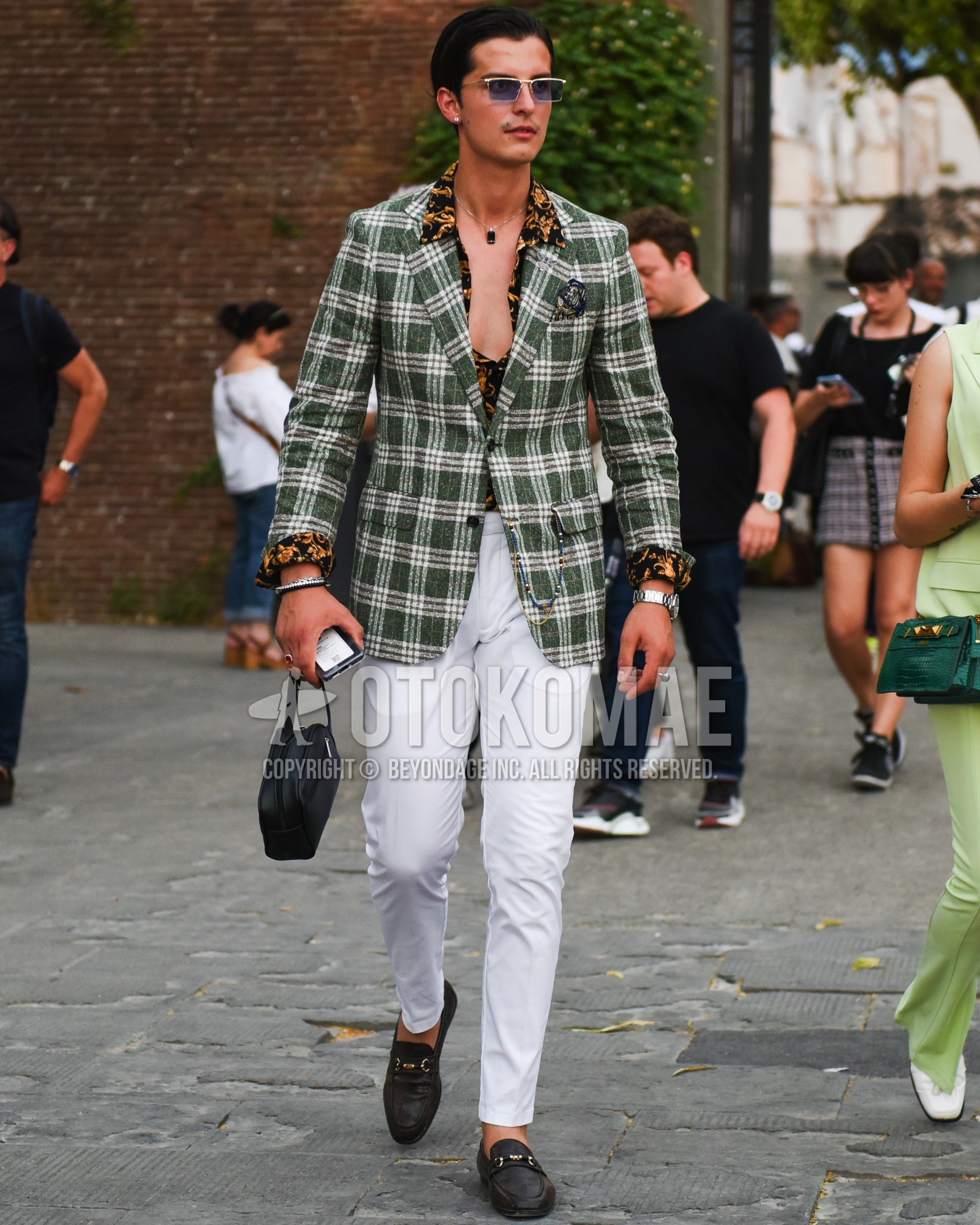 Men's spring summer outfit with gold plain sunglasses, green check tailored jacket, black graphic shirt, white plain cotton pants, brown bit loafers leather shoes.