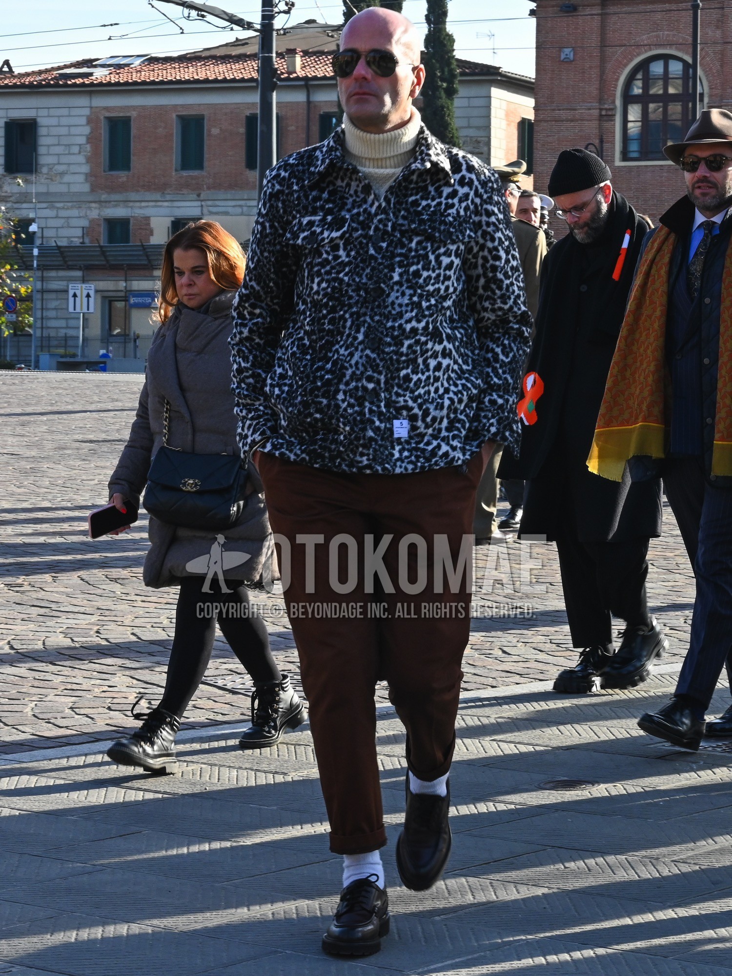 Men's autumn winter outfit with black plain sunglasses, white black leopard coverall, beige plain turtleneck knit, brown plain cotton pants, white plain socks, brown u-tip shoes leather shoes.