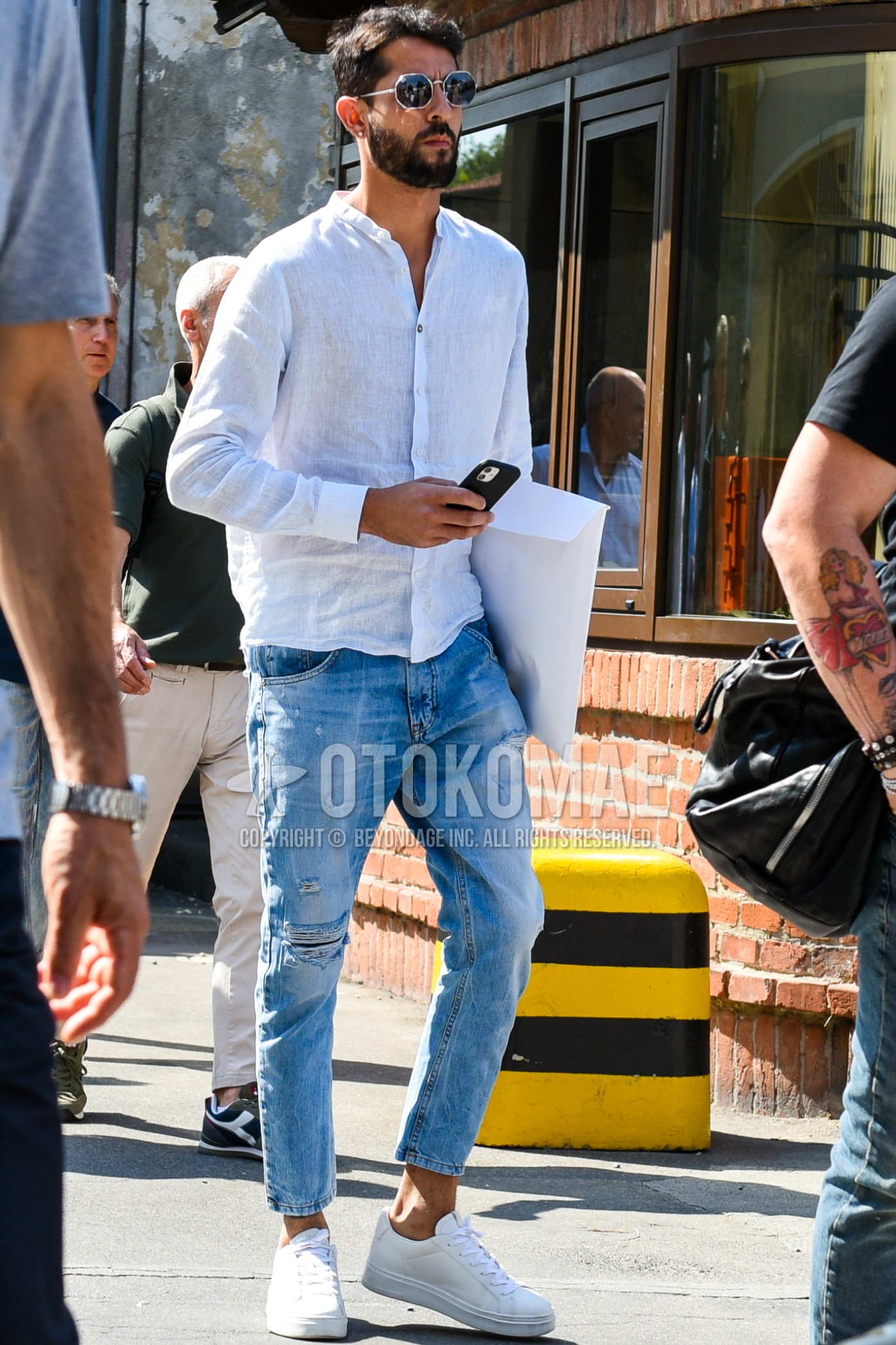 Men's spring summer outfit with silver plain sunglasses, white plain shirt, blue plain damaged jeans, white low-cut sneakers.