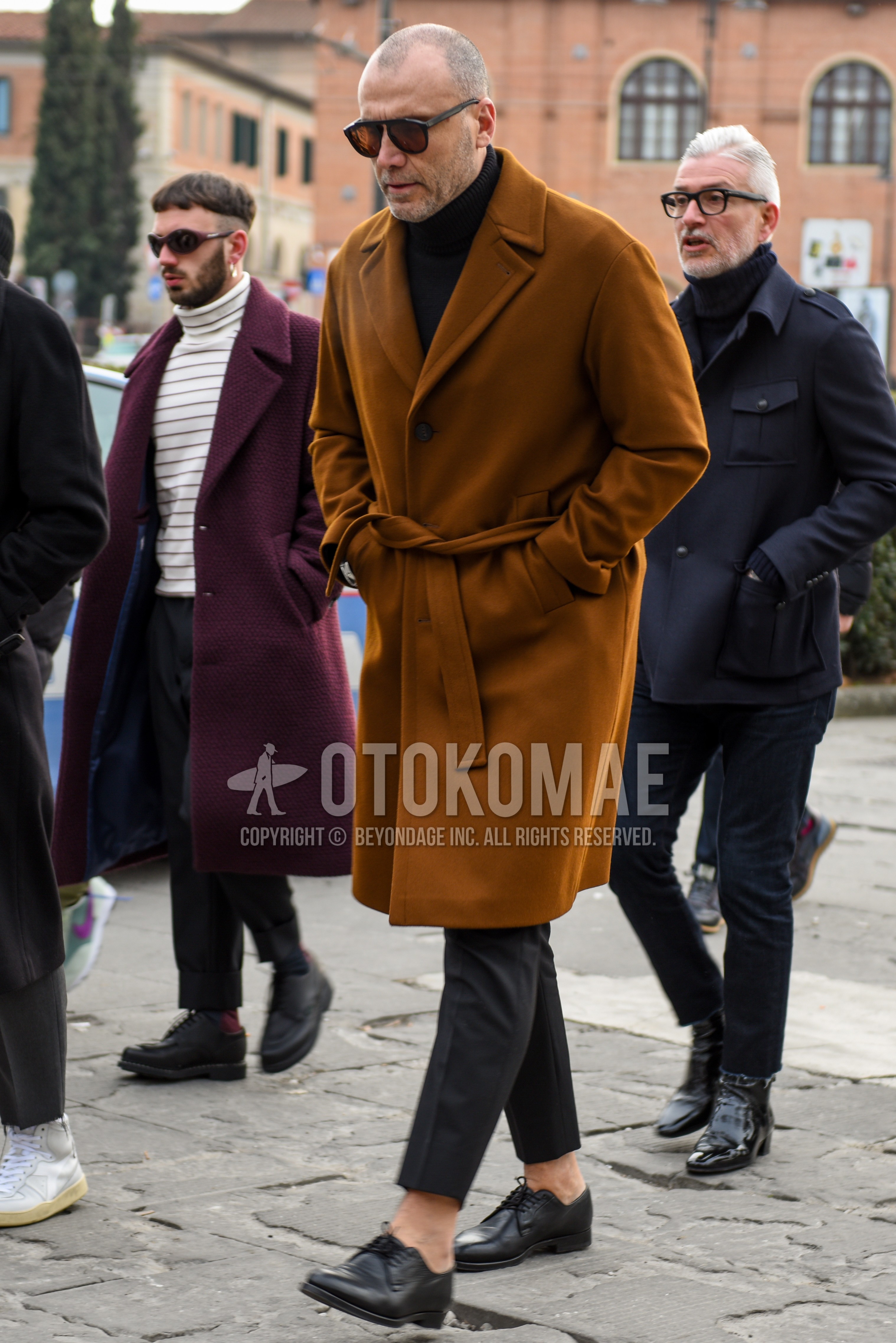 Men's autumn winter outfit with black plain sunglasses, beige plain belted coat, beige plain ulster coat, black plain turtleneck knit, gray plain slacks, gray plain ankle pants, black plain toe leather shoes.