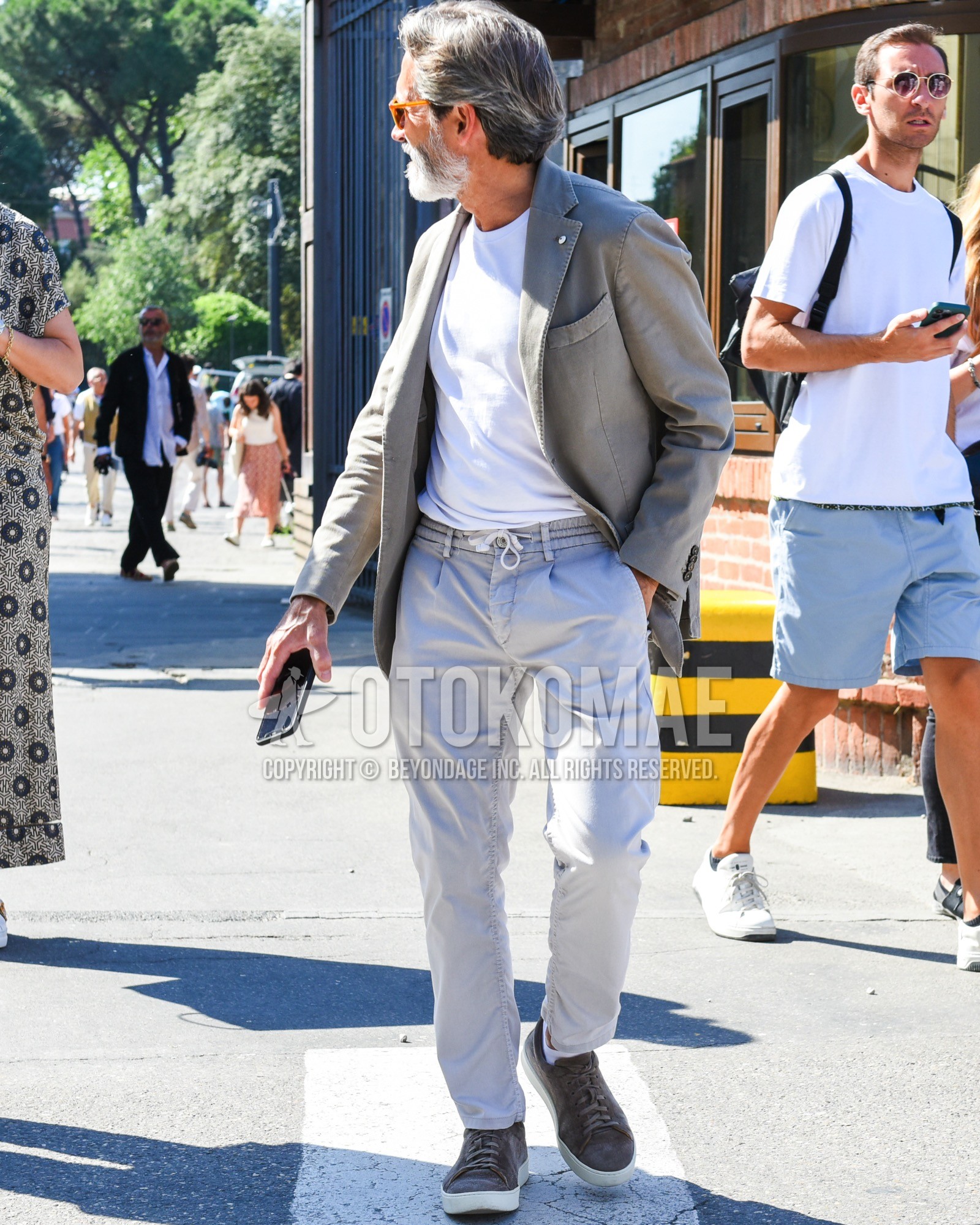 Men's spring summer outfit with yellow plain sunglasses, gray plain tailored jacket, white plain t-shirt, gray plain easy pants, white plain socks, brown low-cut sneakers.
