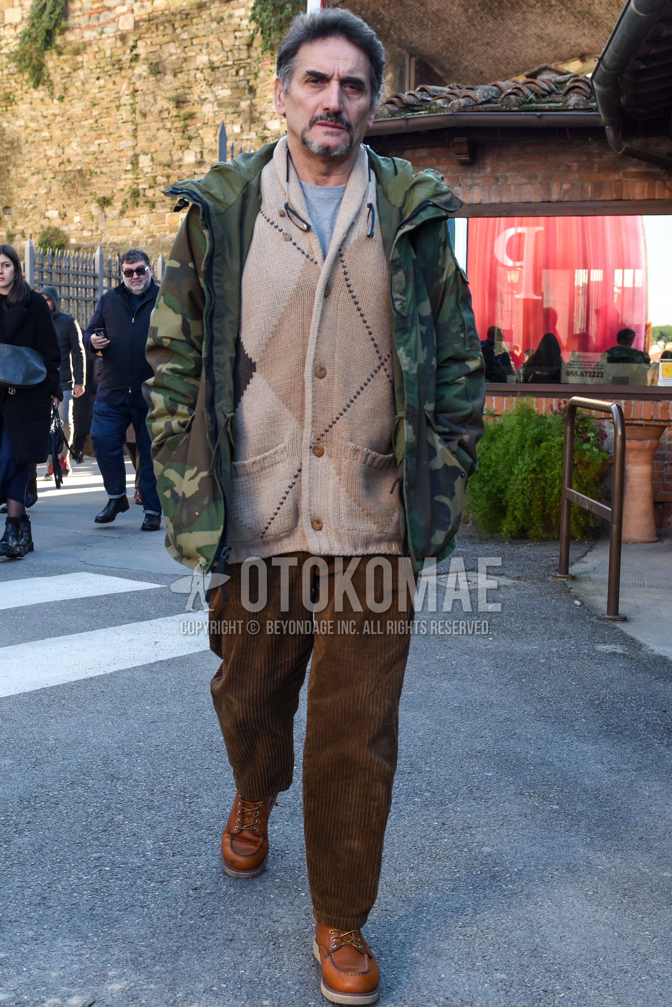 Men's autumn winter outfit with olive green camouflage mountain parka, beige tops/innerwear cardigan, gray plain t-shirt, brown plain winter pants (corduroy,velour), brown work boots.