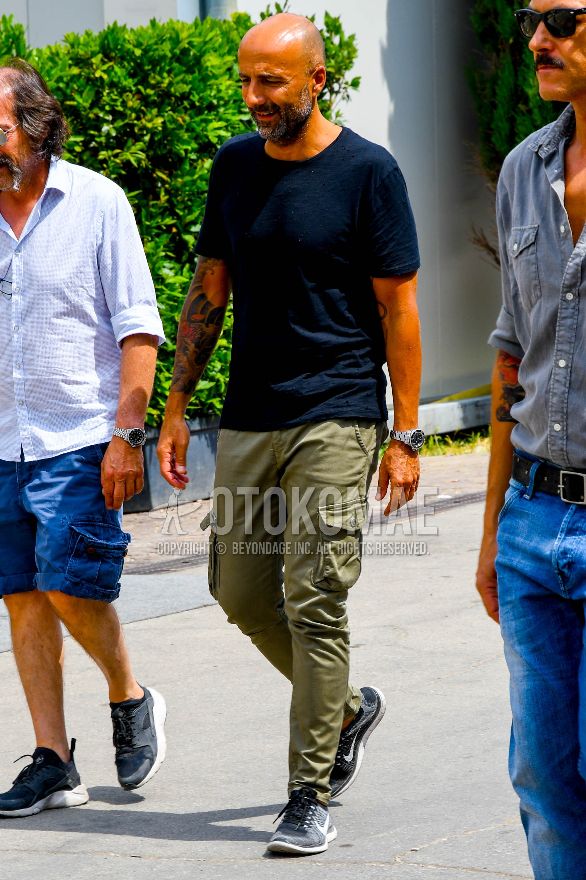 Men's summer outfit with navy plain t-shirt, olive green plain cargo pants, black low-cut sneakers.