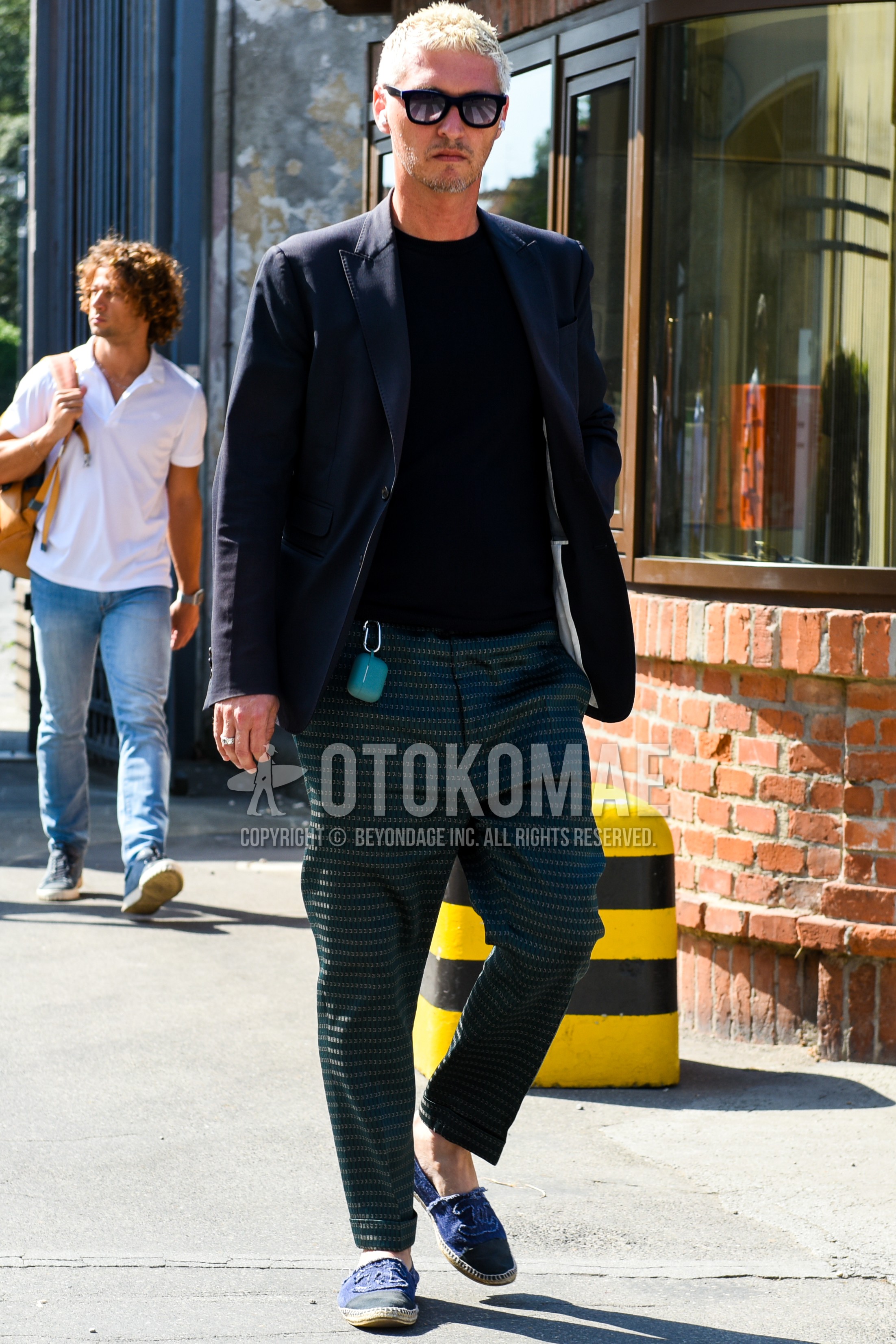 Men's spring summer autumn outfit with black plain sunglasses, navy plain tailored jacket, green horizontal stripes sweatpants, navy low-cut sneakers.