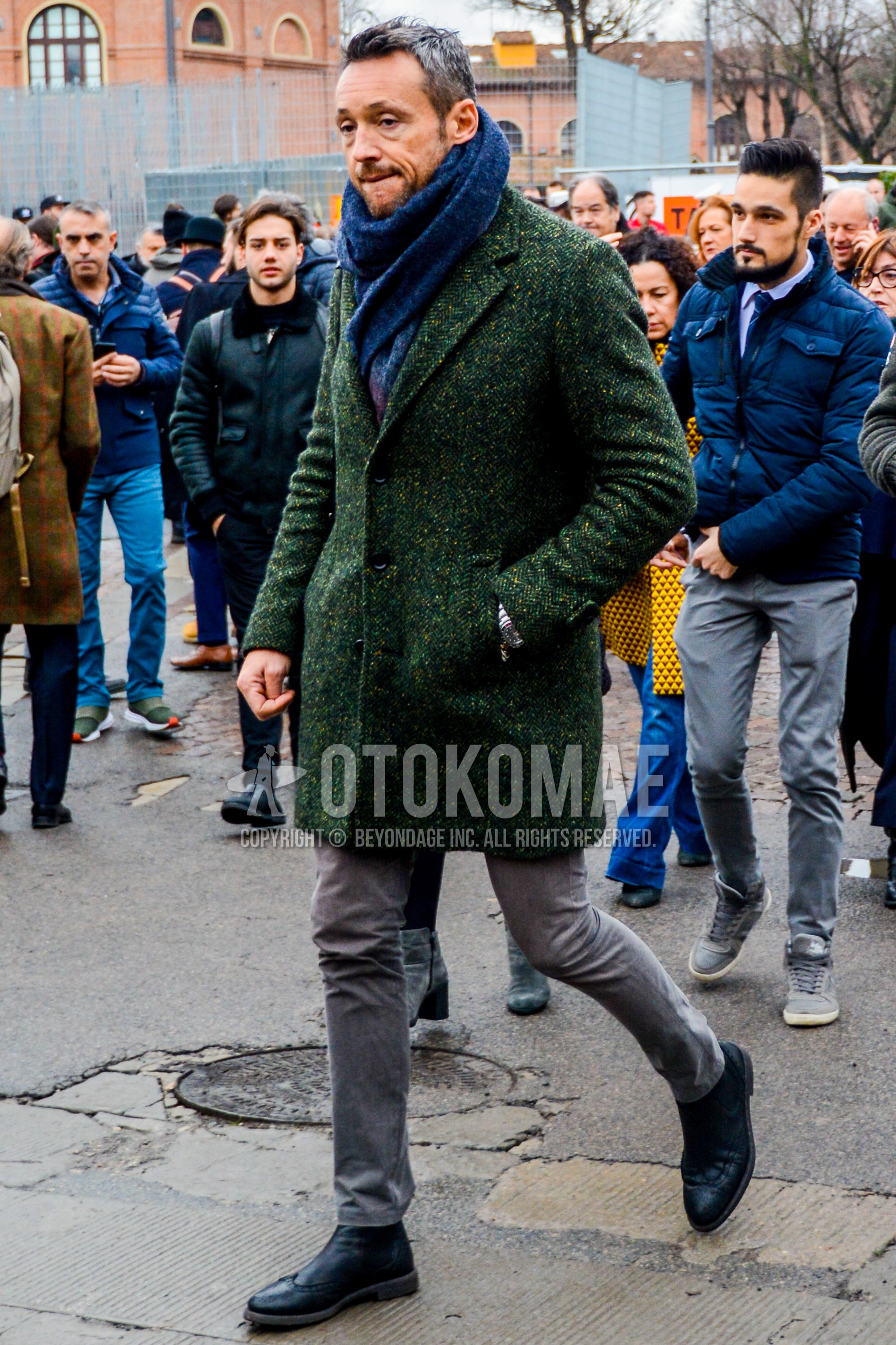 Men's autumn winter outfit with gray plain scarf, green herringbone chester coat, gray plain cotton pants, black  boots.