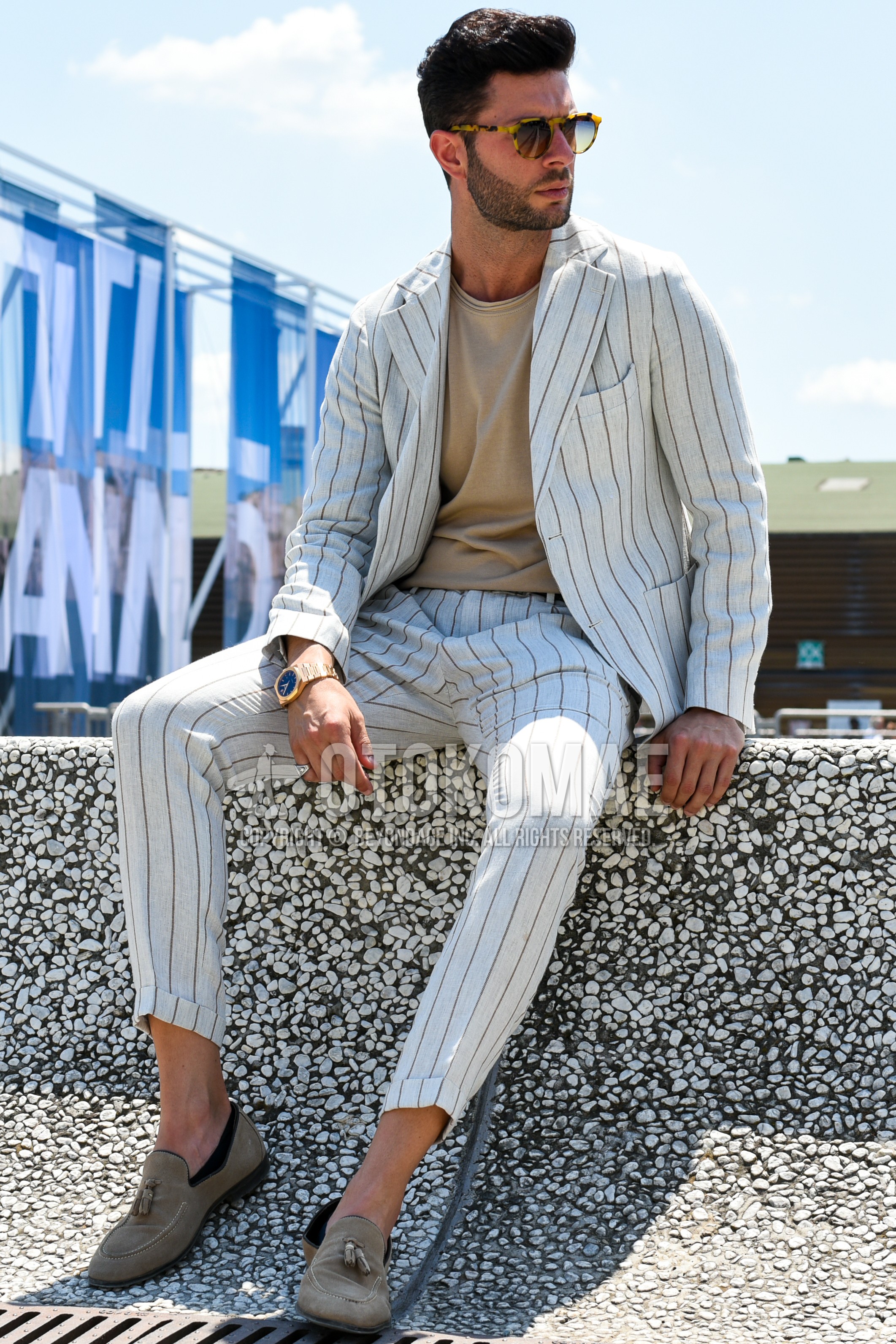 Men's spring summer outfit with brown tortoiseshell sunglasses, beige plain t-shirt, beige tassel loafers leather shoes, beige stripes suit.
