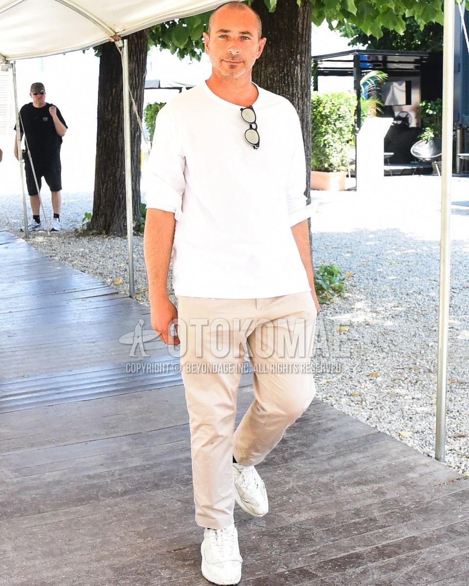 Men's spring summer outfit with white plain long sleeve t-shirt, beige plain cotton pants, white low-cut sneakers.