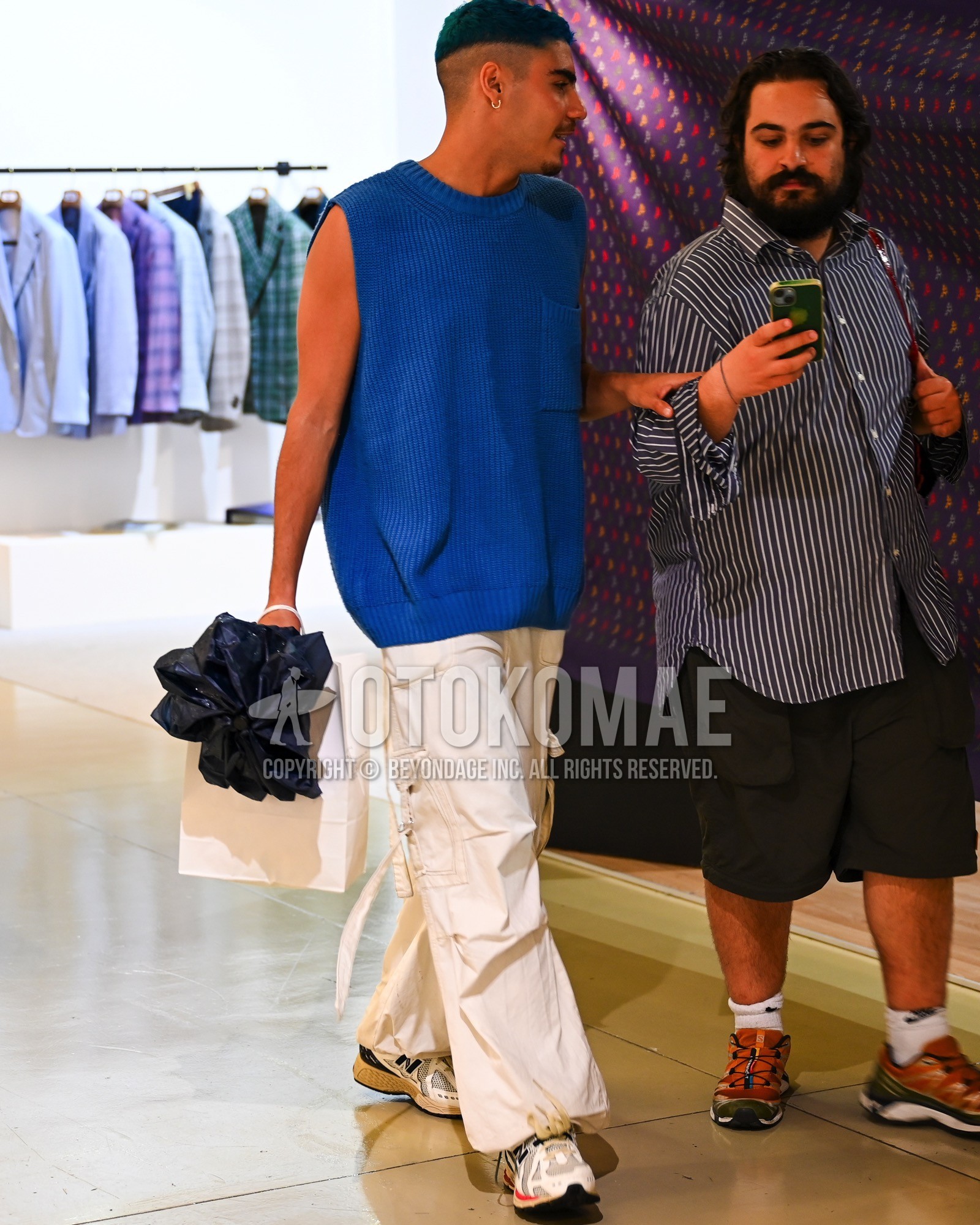 Men's spring summer outfit with blue plain casual vest, white plain cargo pants, white low-cut sneakers.