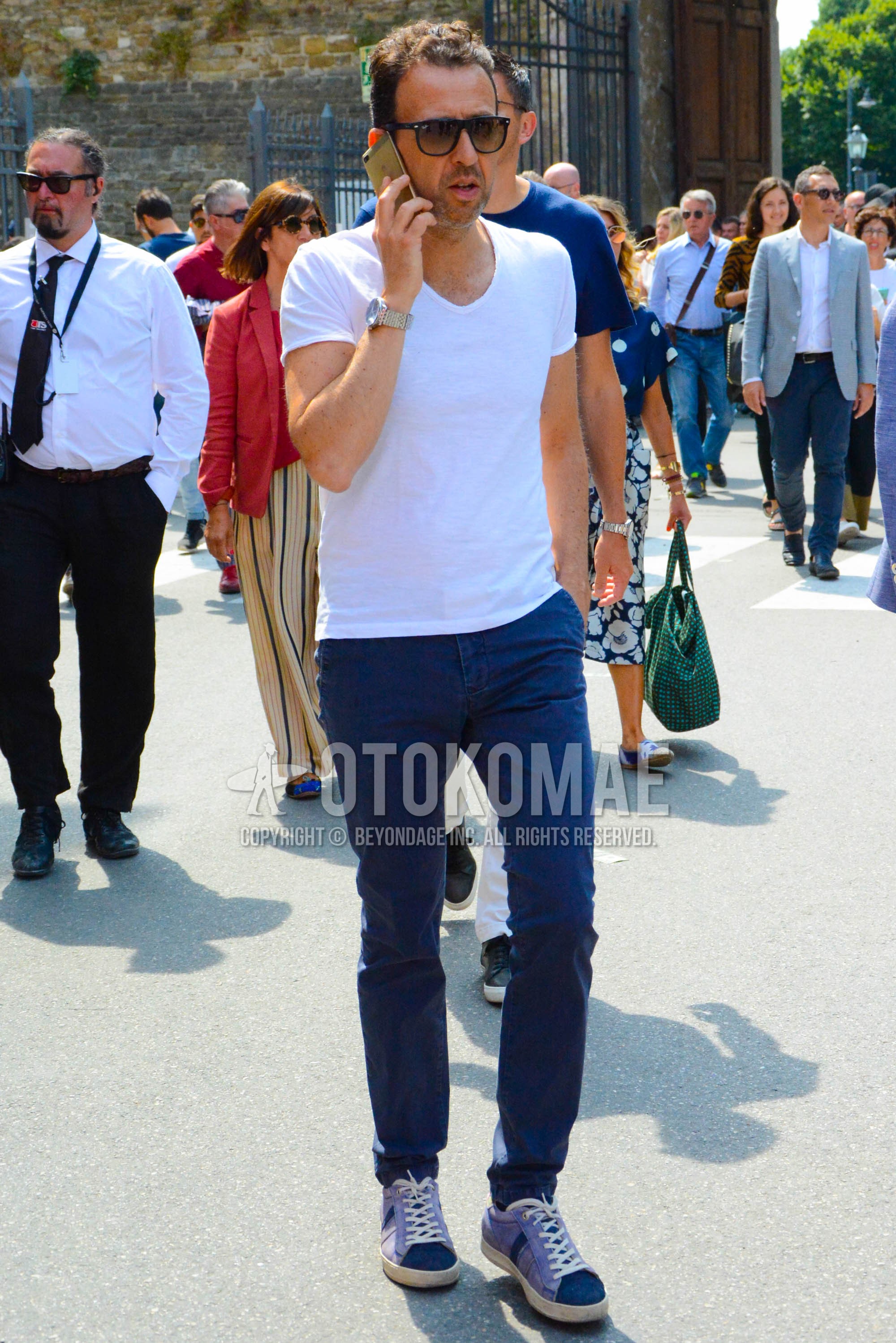 Men's spring summer outfit with black plain sunglasses, white plain t-shirt, navy plain chinos, navy low-cut sneakers.