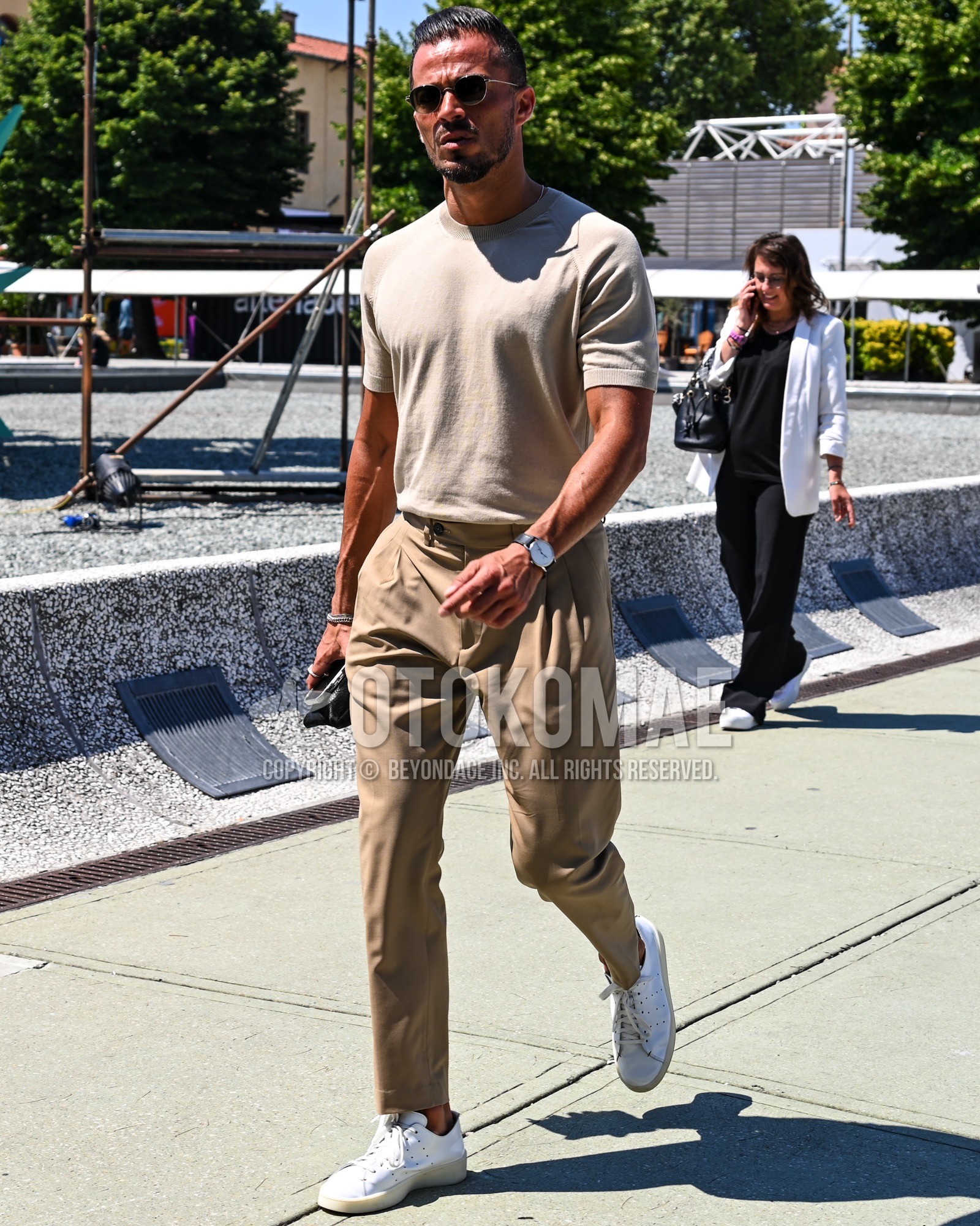 Men's spring summer outfit with beige plain t-shirt, beige plain beltless pants, white low-cut sneakers.
