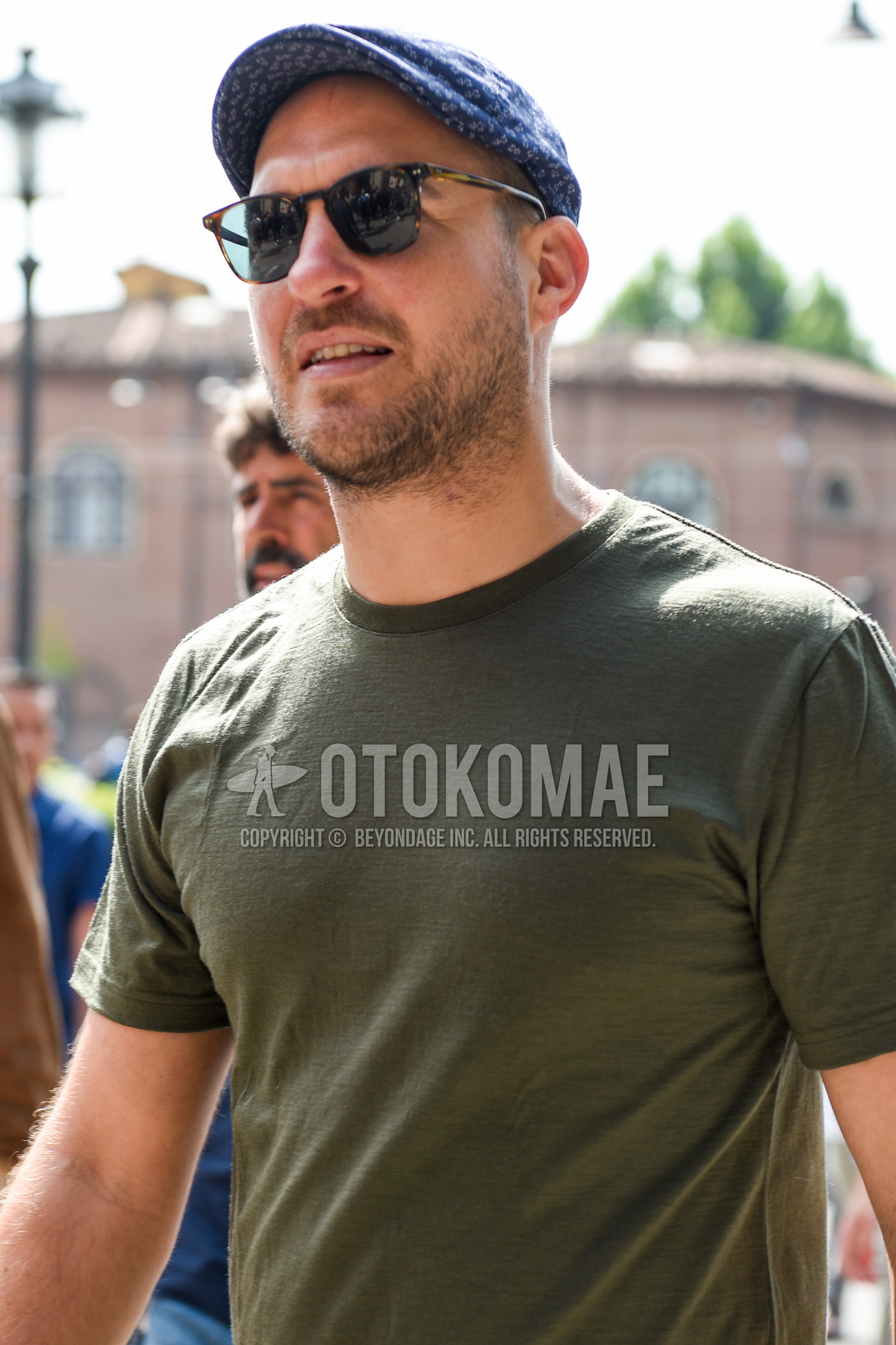 Men's summer outfit with blue cap, brown black plain sunglasses, olive green plain t-shirt.