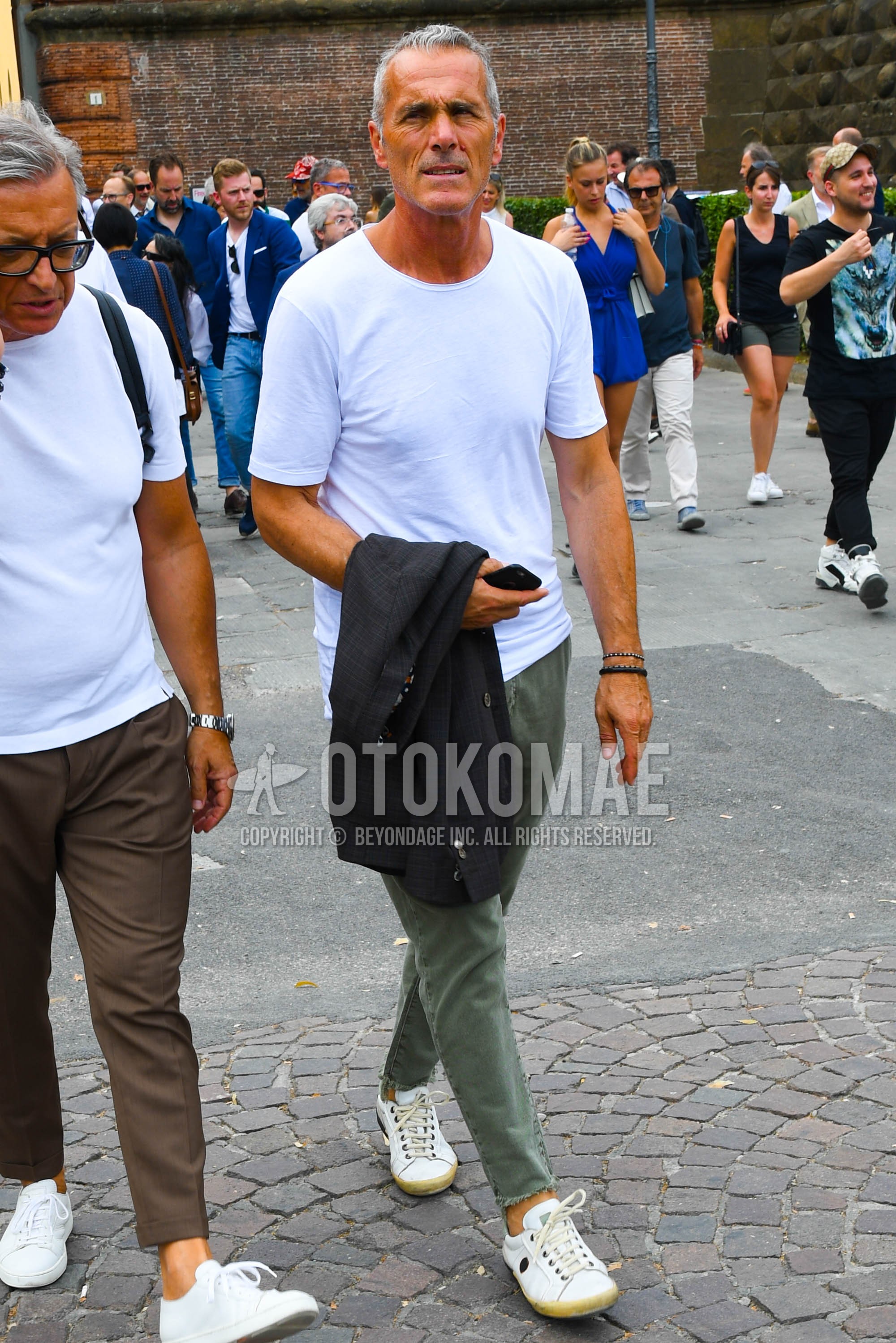 Men's summer outfit with white plain t-shirt, olive green plain ankle pants, plain chinos, white low-cut sneakers.