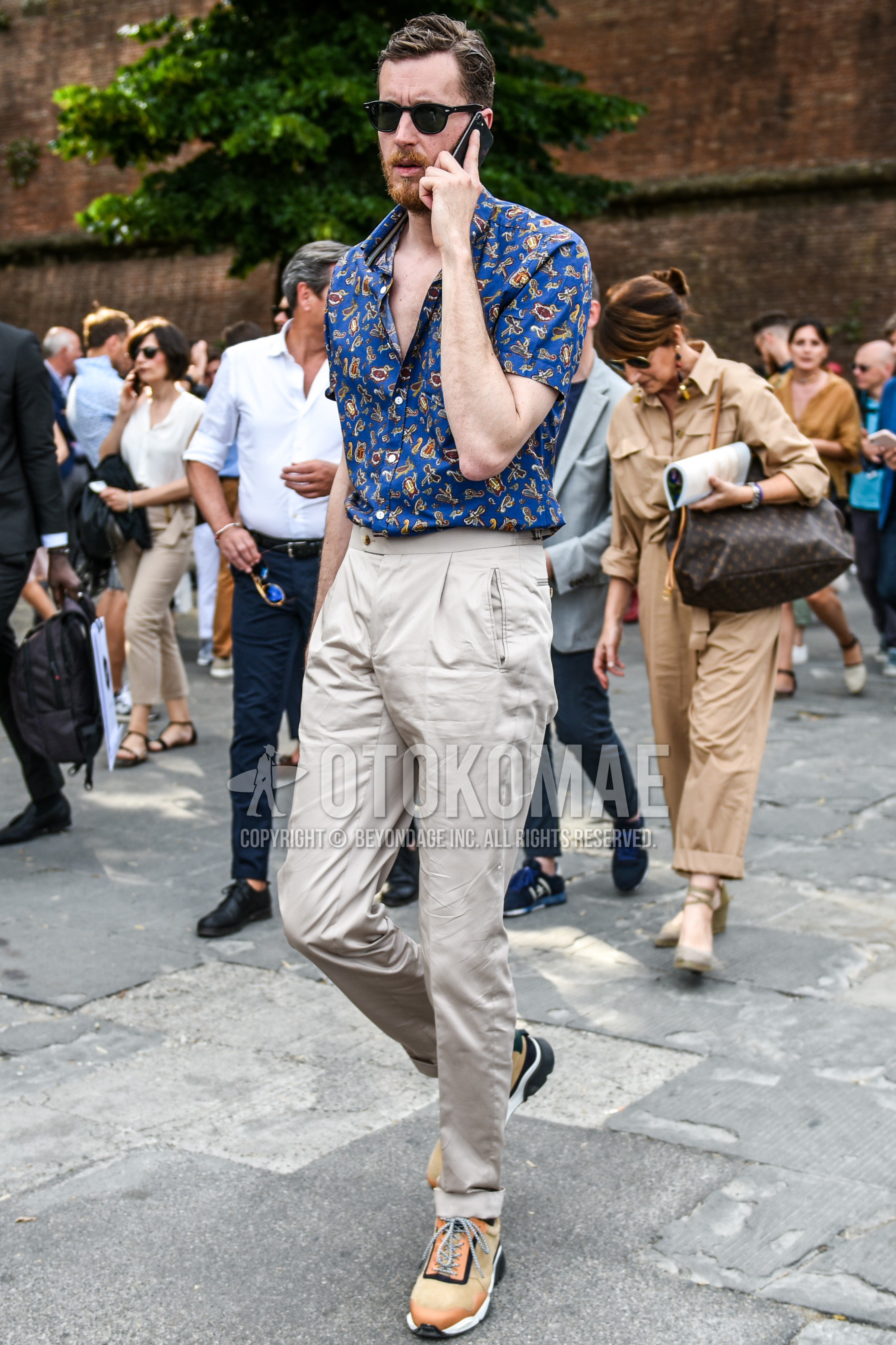 Men's summer outfit with plain sunglasses, blue tops/innerwear shirt, beige plain cotton pants, orange low-cut sneakers.