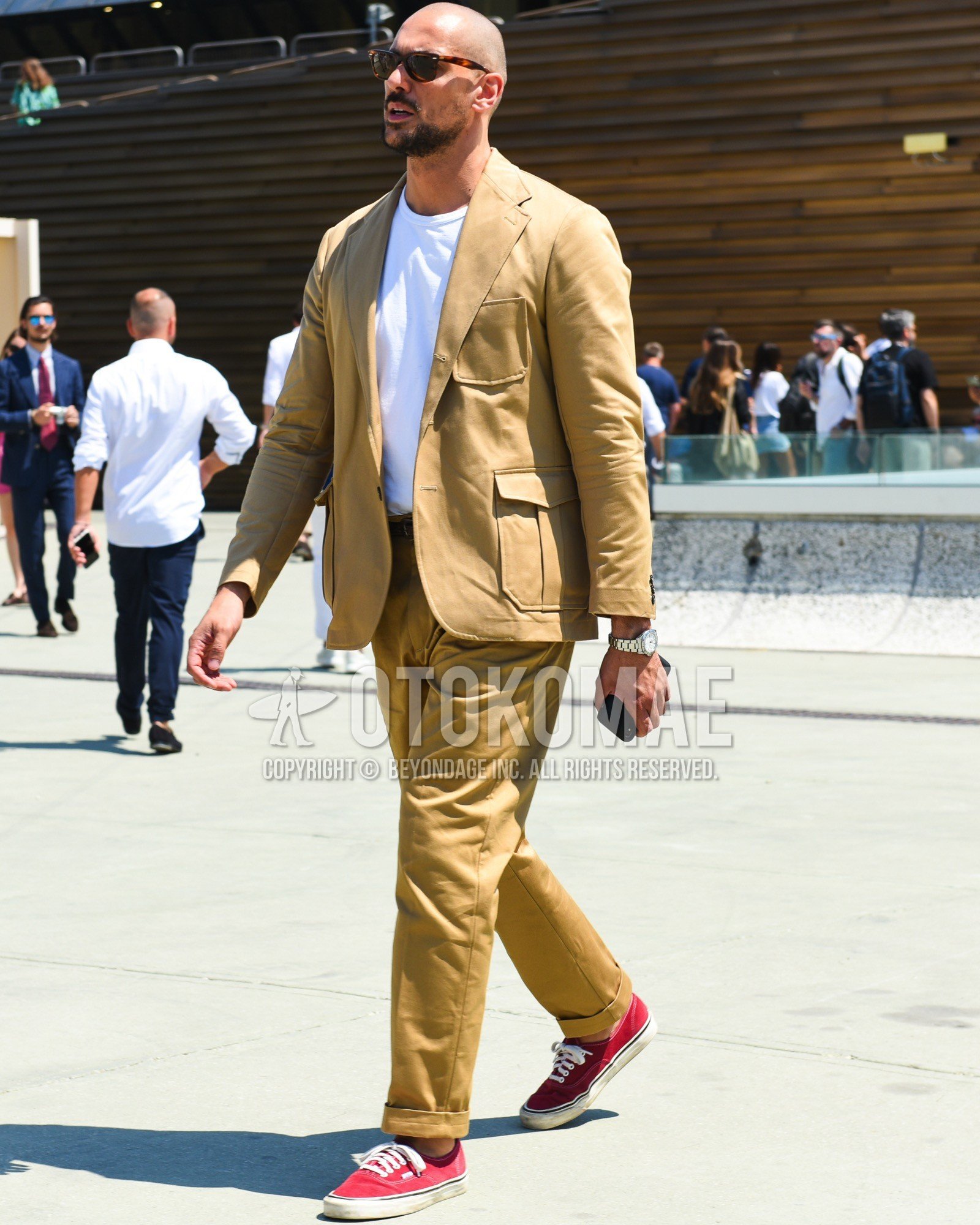 Men's spring summer outfit with brown tortoiseshell sunglasses, white plain t-shirt, brown plain leather belt, red high-cut sneakers, beige plain casual setup.