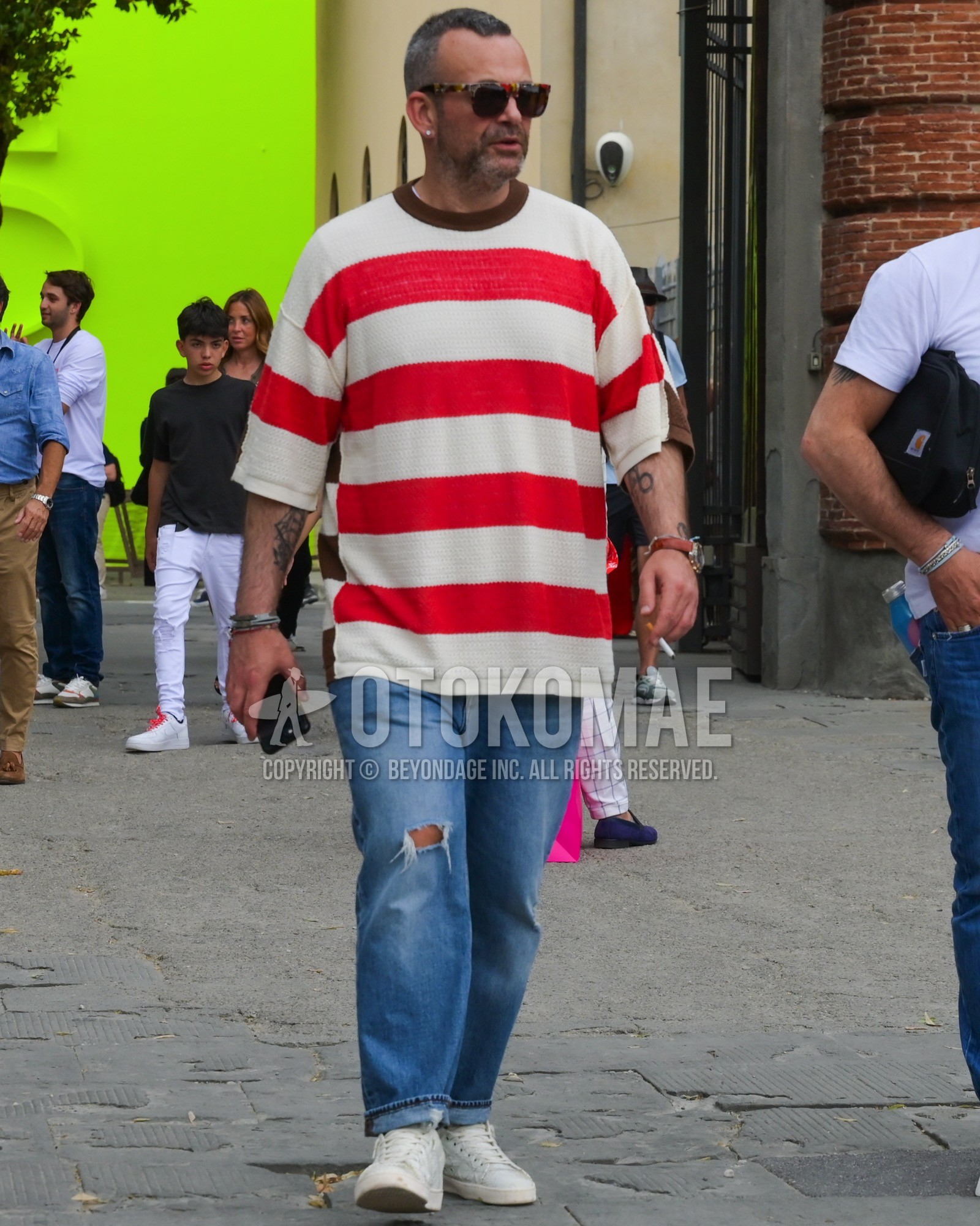 Men's spring summer outfit with black plain sunglasses, white red horizontal stripes t-shirt, blue plain damaged jeans, white low-cut sneakers.