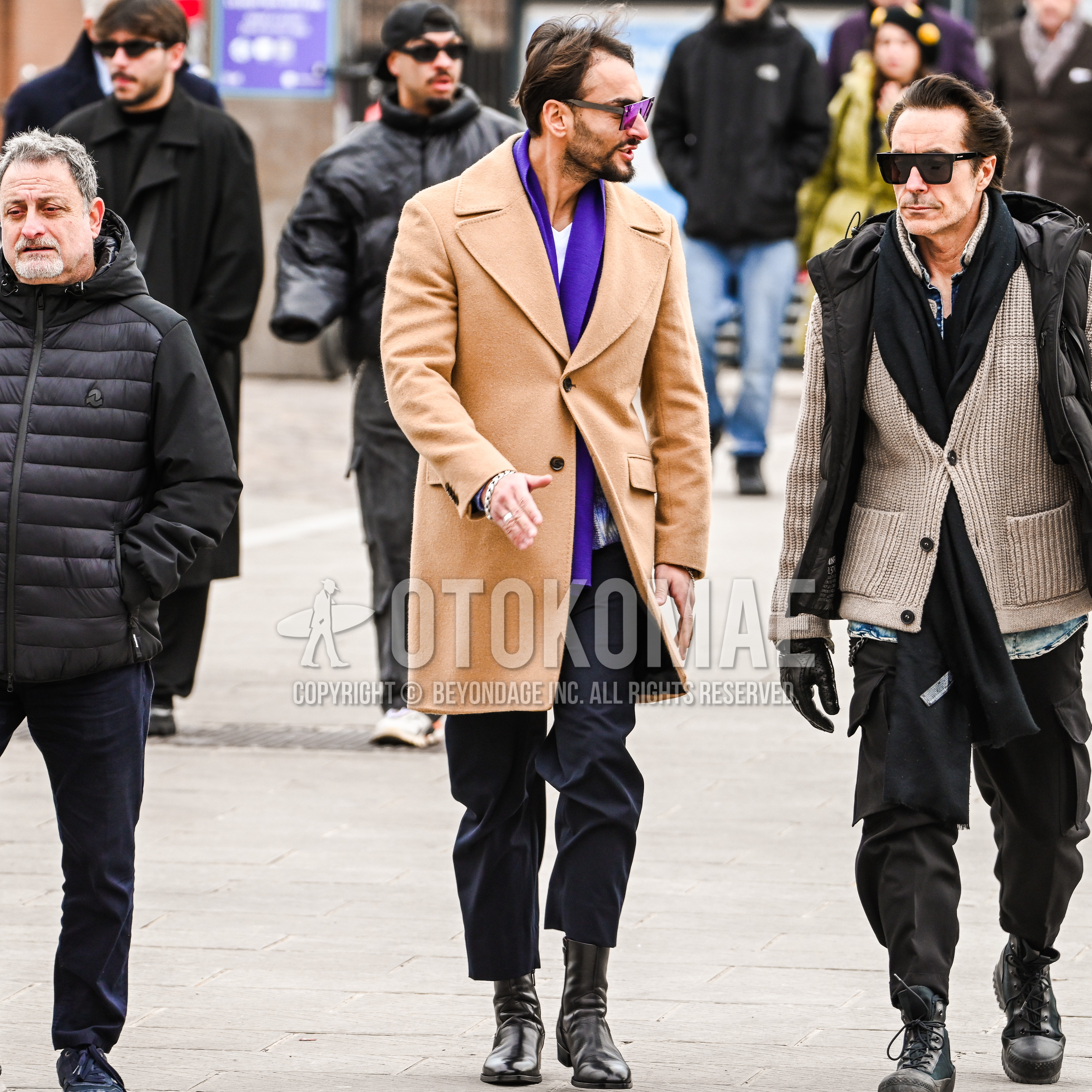 Men's autumn winter outfit with gray plain sunglasses, purple plain scarf, beige plain ulster coat, white plain long sleeve t-shirt, navy plain chinos, black  boots.