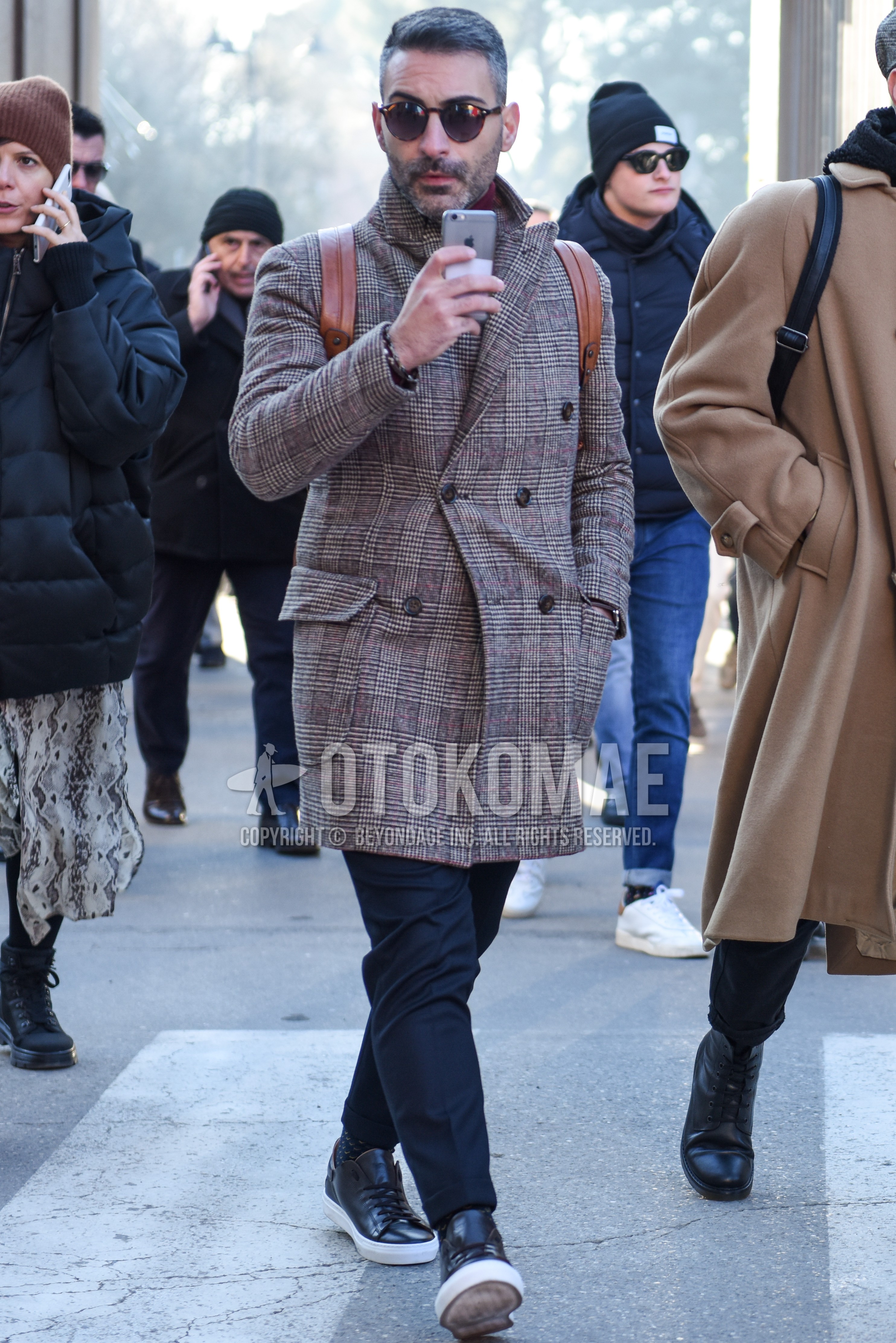 Men's autumn winter outfit with brown tortoiseshell sunglasses, gray check chester coat, dark gray plain slacks, dark gray plain ankle pants, black low-cut sneakers.