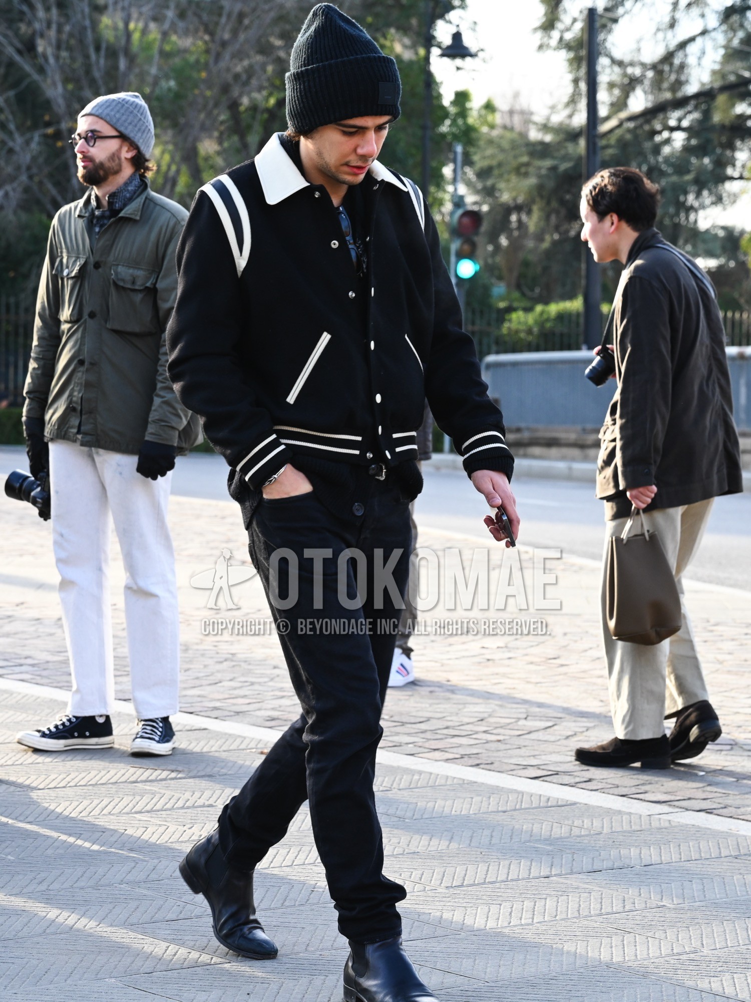 Men's autumn winter outfit with black plain knit cap, black plain stadium jacket, black plain cardigan, black plain denim/jeans, black side-gore boots.