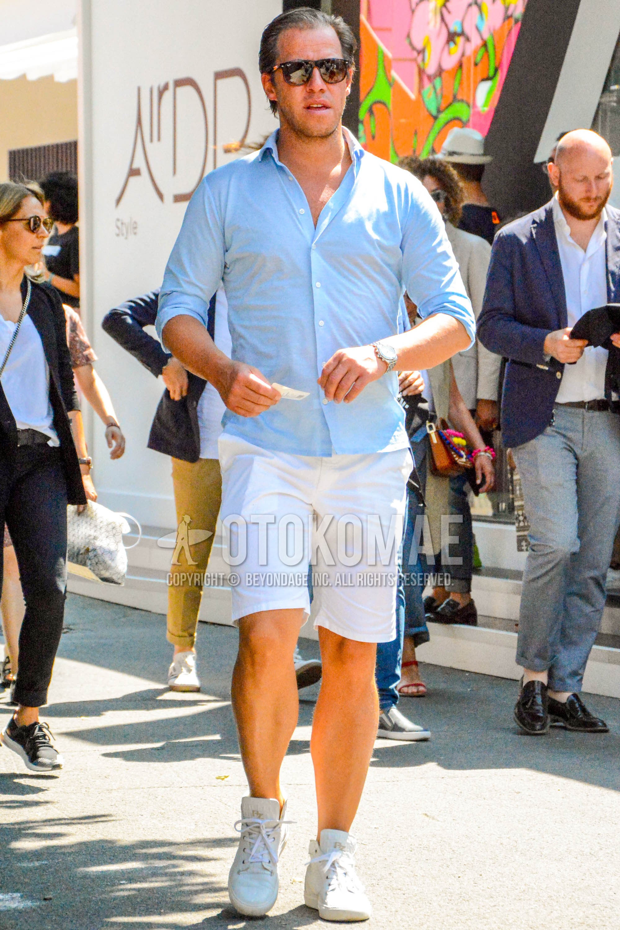 Men's spring summer outfit with plain sunglasses, light blue plain shirt, white plain short pants, white high-cut sneakers.