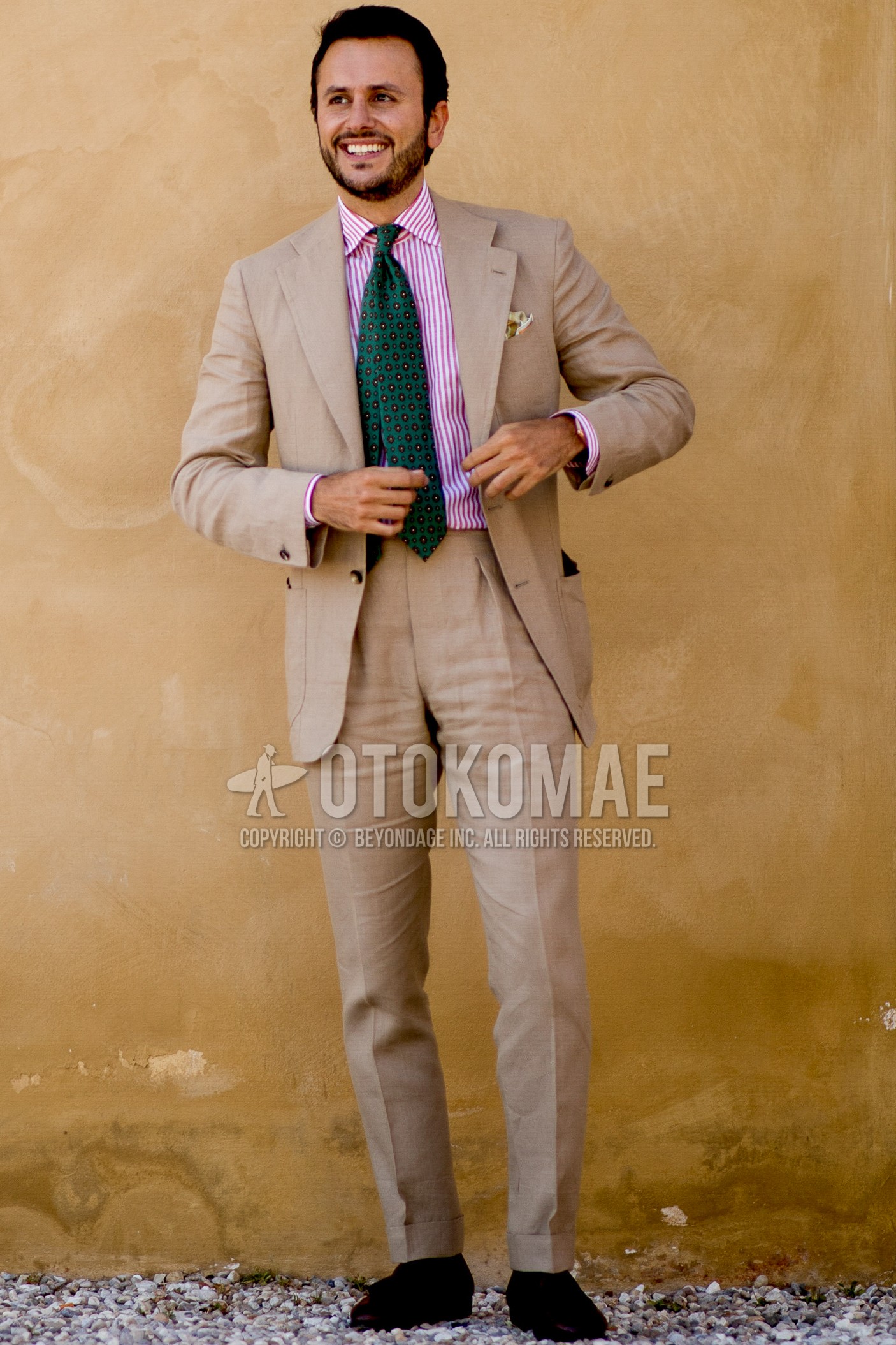 Men's spring summer outfit with pink red stripes shirt, black plain socks, brown tassel loafers leather shoes, beige plain suit, green small crest necktie.
