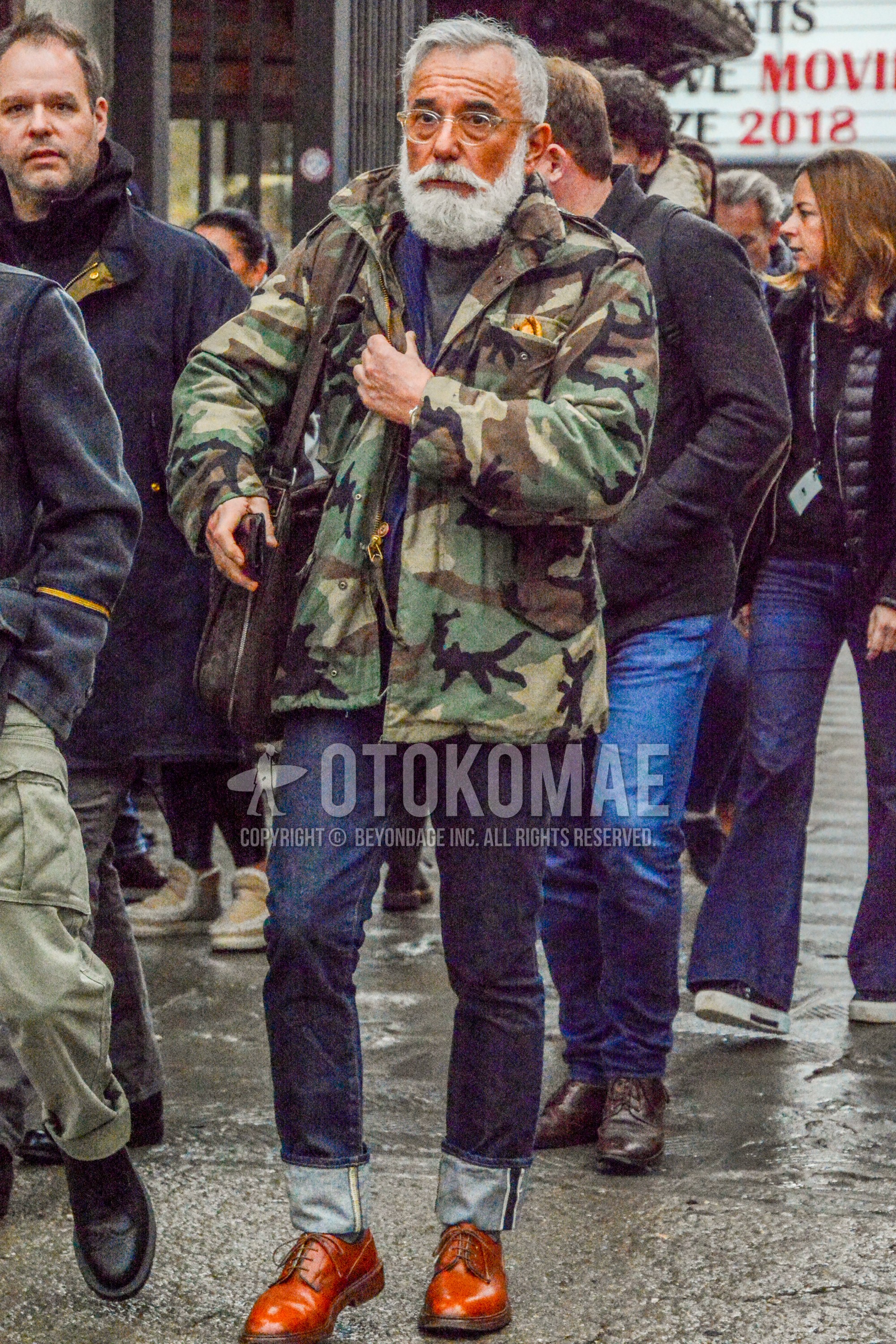 Men's winter outfit with plain glasses, multi-color camouflage M-65, navy plain tailored jacket, navy plain denim/jeans, brown plain toe leather shoes.