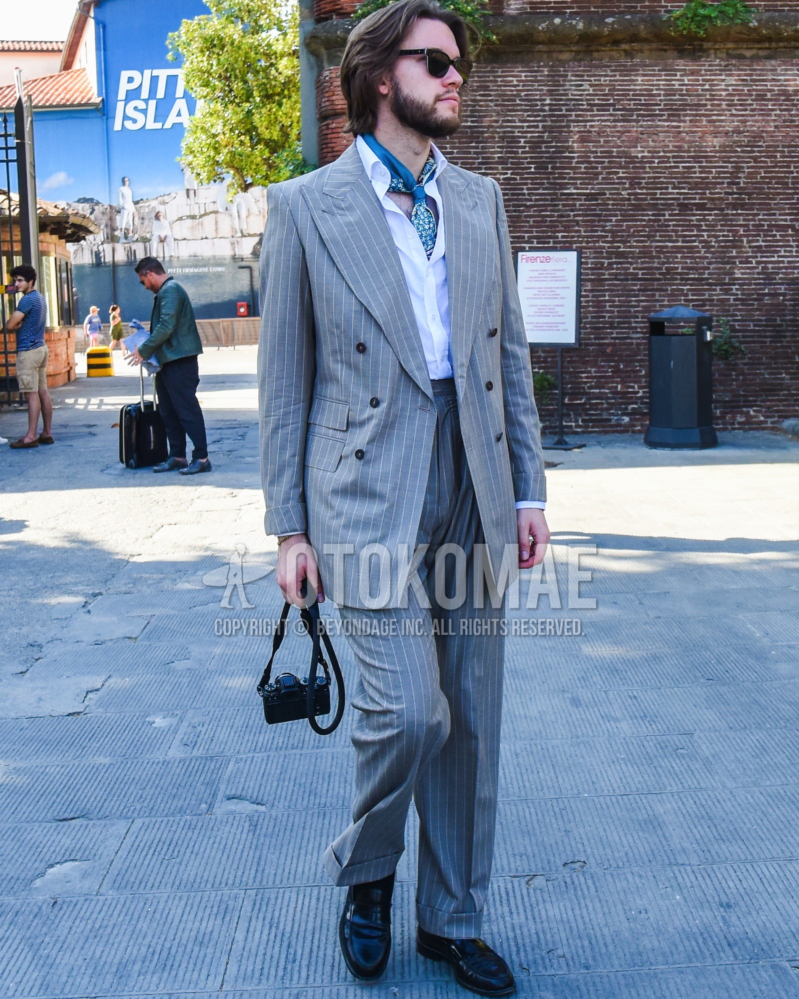 Men's spring summer outfit with black plain sunglasses, blue scarf scarf, white plain shirt, black coin loafers leather shoes, gray stripes suit.