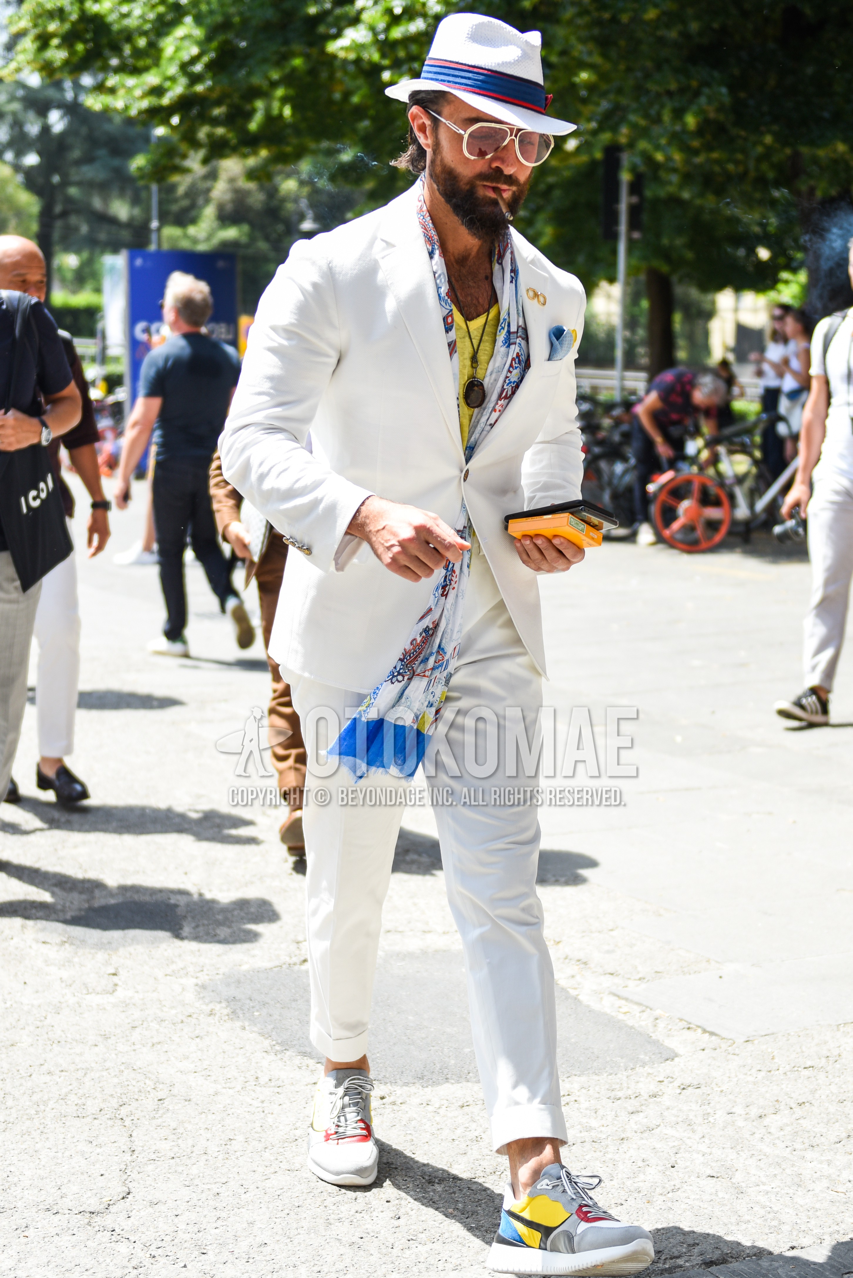 Men's spring summer outfit with white plain hat, gold brown plain sunglasses, multi-color scarf scarf, yellow plain t-shirt, multi-color low-cut sneakers, white plain suit.