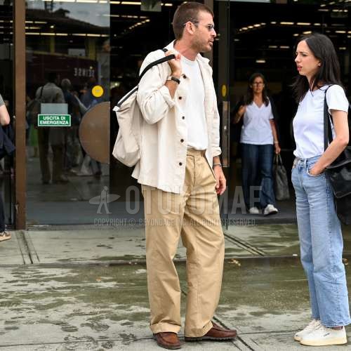 シルバー無地のサングラス、白無地のシャツ、白無地のTシャツ、ベージュ無地のコットンパンツ、ベージュ無地のベルトレスパンツ、ブラウンコインローファーの革靴、白バッグのトートバッグを合わせた夏春のメンズコーデ・着こなし。