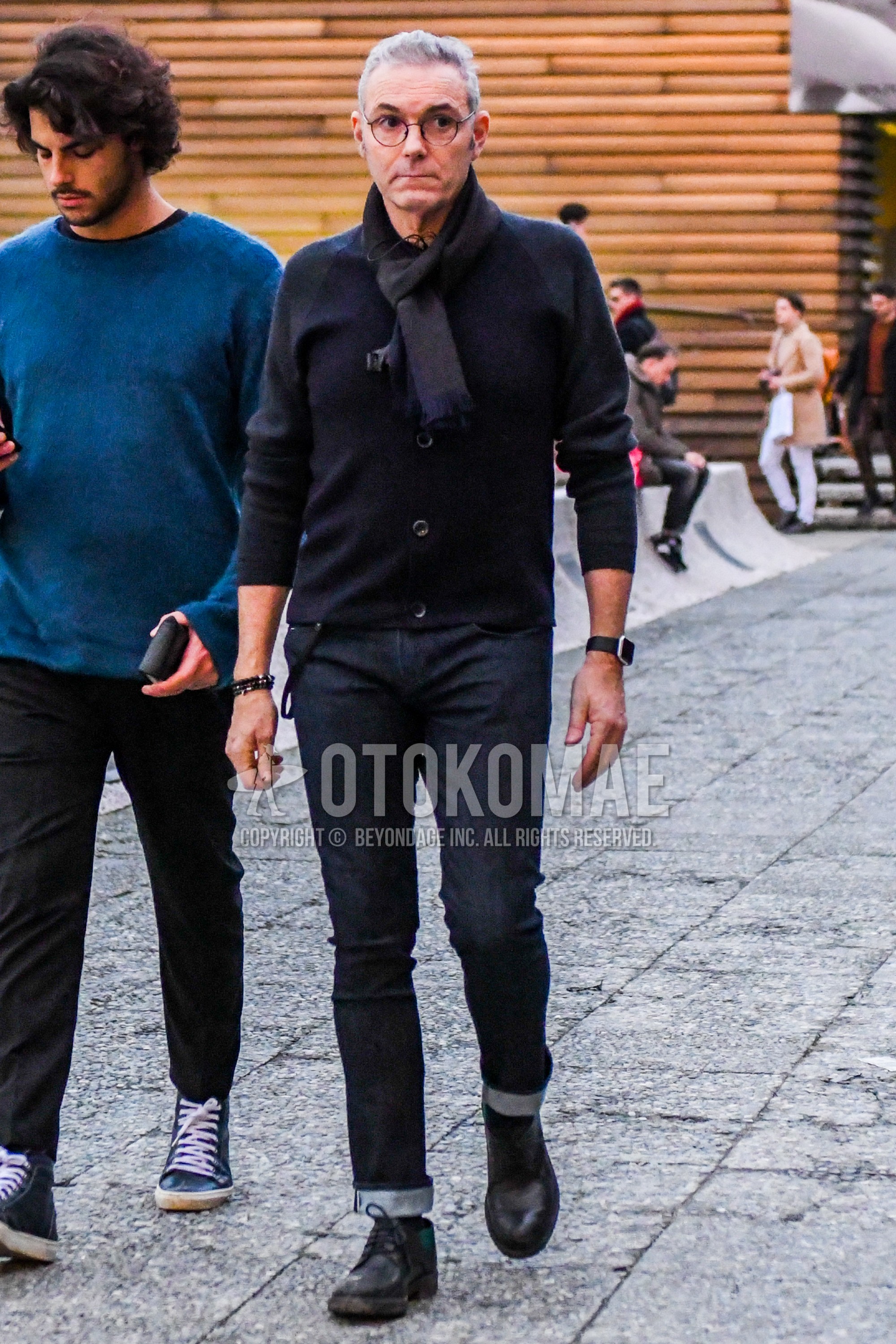 Men's autumn outfit with plain glasses, black plain scarf, black plain cardigan, navy plain denim/jeans, black chukka boots.