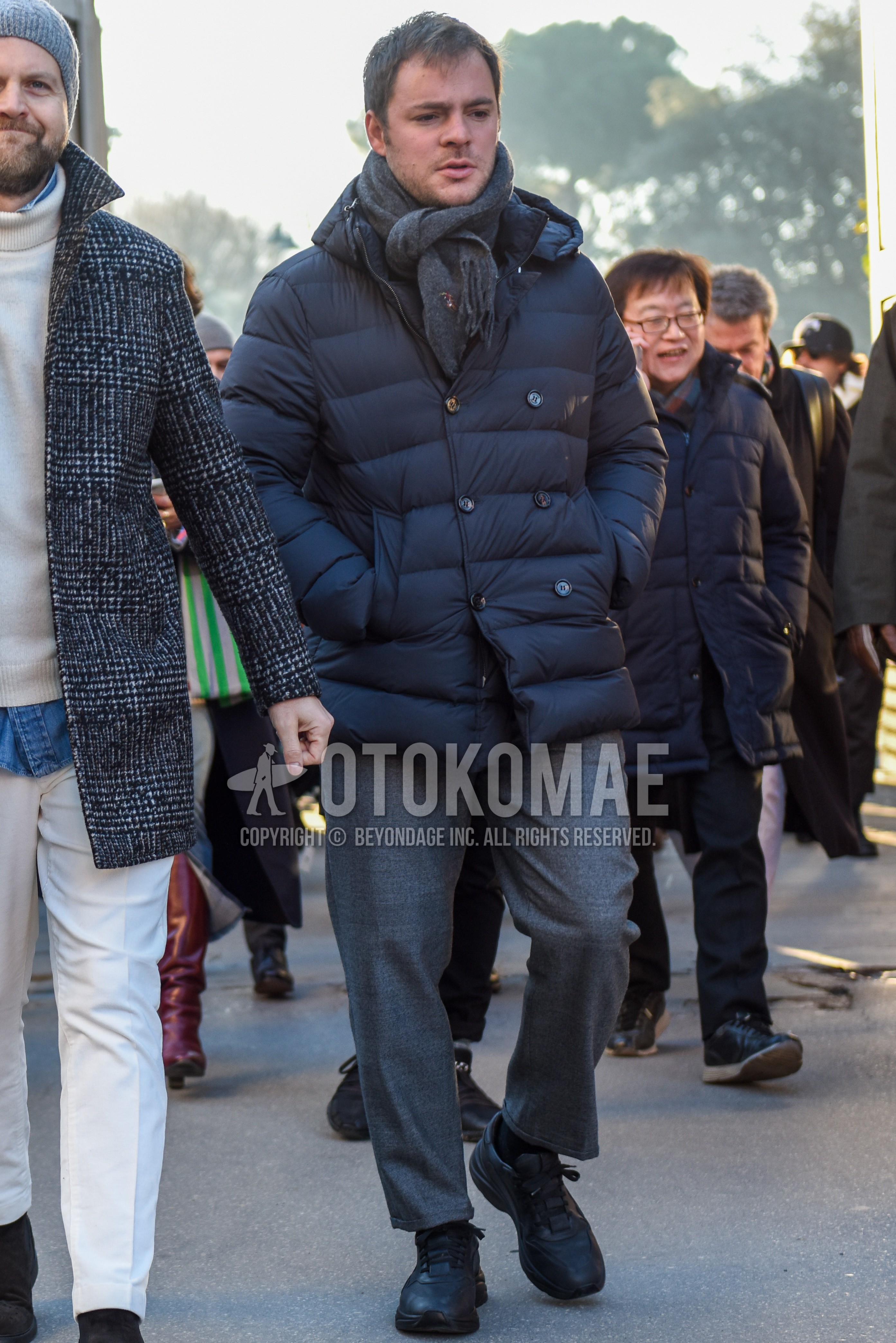 Men's autumn winter outfit with gray plain scarf, dark gray plain down jacket, gray plain slacks, gray plain cropped pants, black plain socks, black low-cut sneakers.