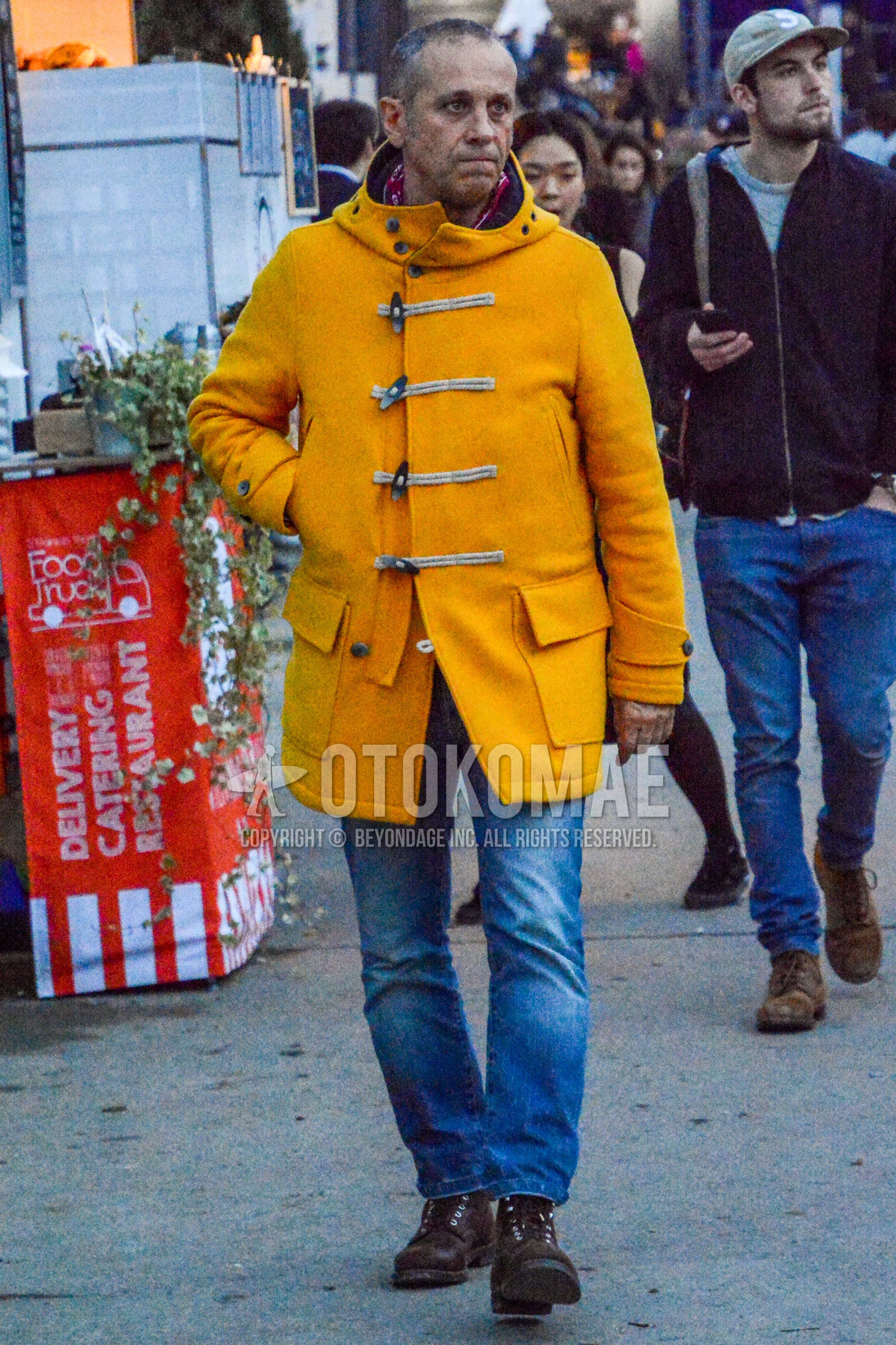 Men's winter outfit with yellow plain duffle coat, blue plain denim/jeans, brown work boots.
