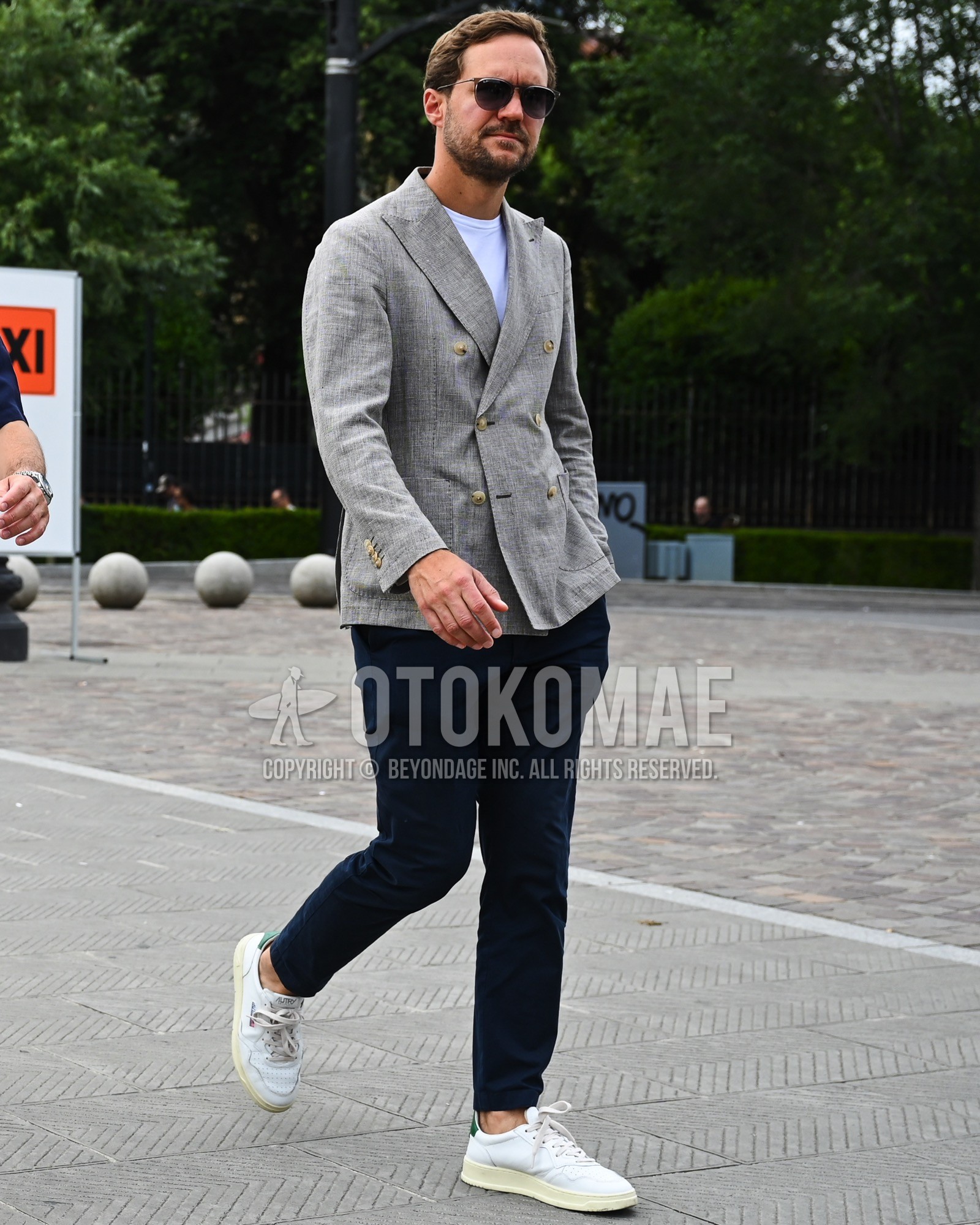 Men's spring summer autumn outfit with black plain sunglasses, gray plain tailored jacket, white plain t-shirt, navy plain chinos, white low-cut sneakers.