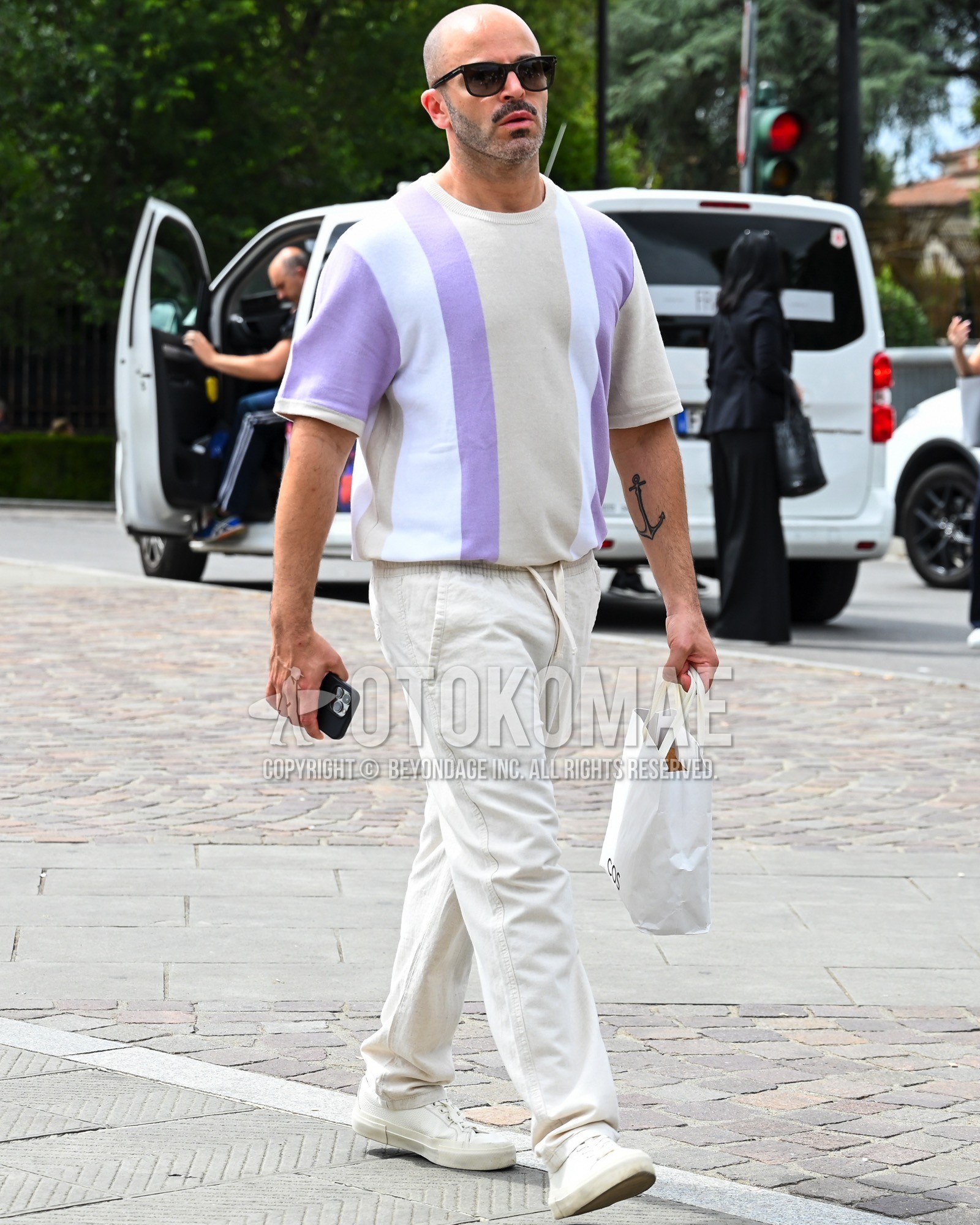 Men's spring summer outfit with black plain sunglasses, white purple stripes t-shirt, white plain wide pants.